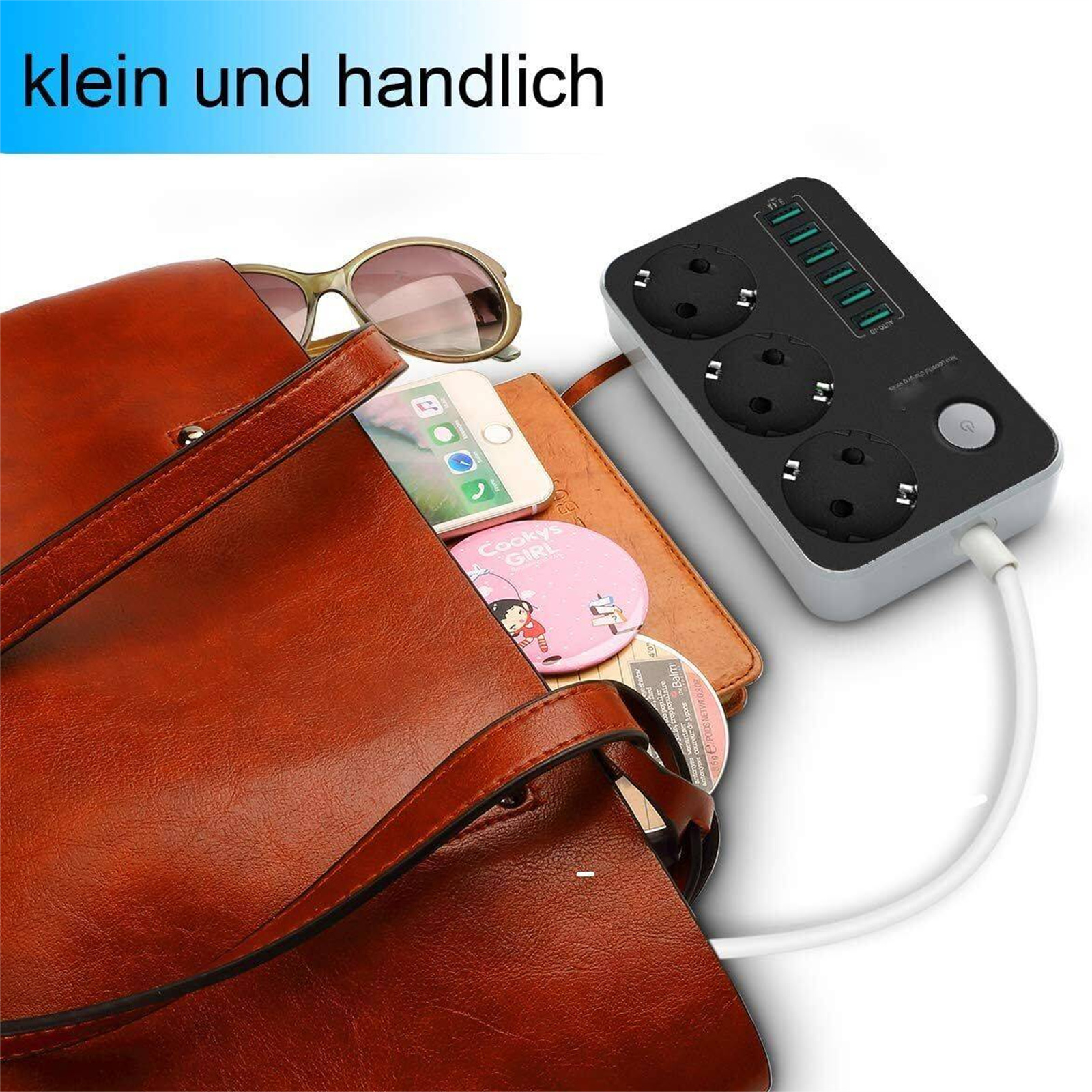 Eine kleine schwarze Steckdosenleiste in einer braunen Tasche mit Gegenständen und Text.