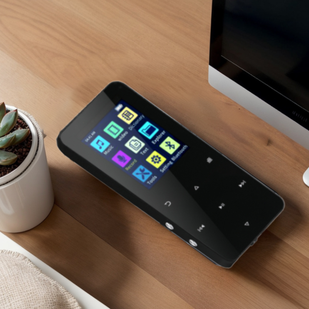 Ein schwarzer MP3-Player mit Farbbildschirm liegt auf einem Holztisch neben einer Pflanze.