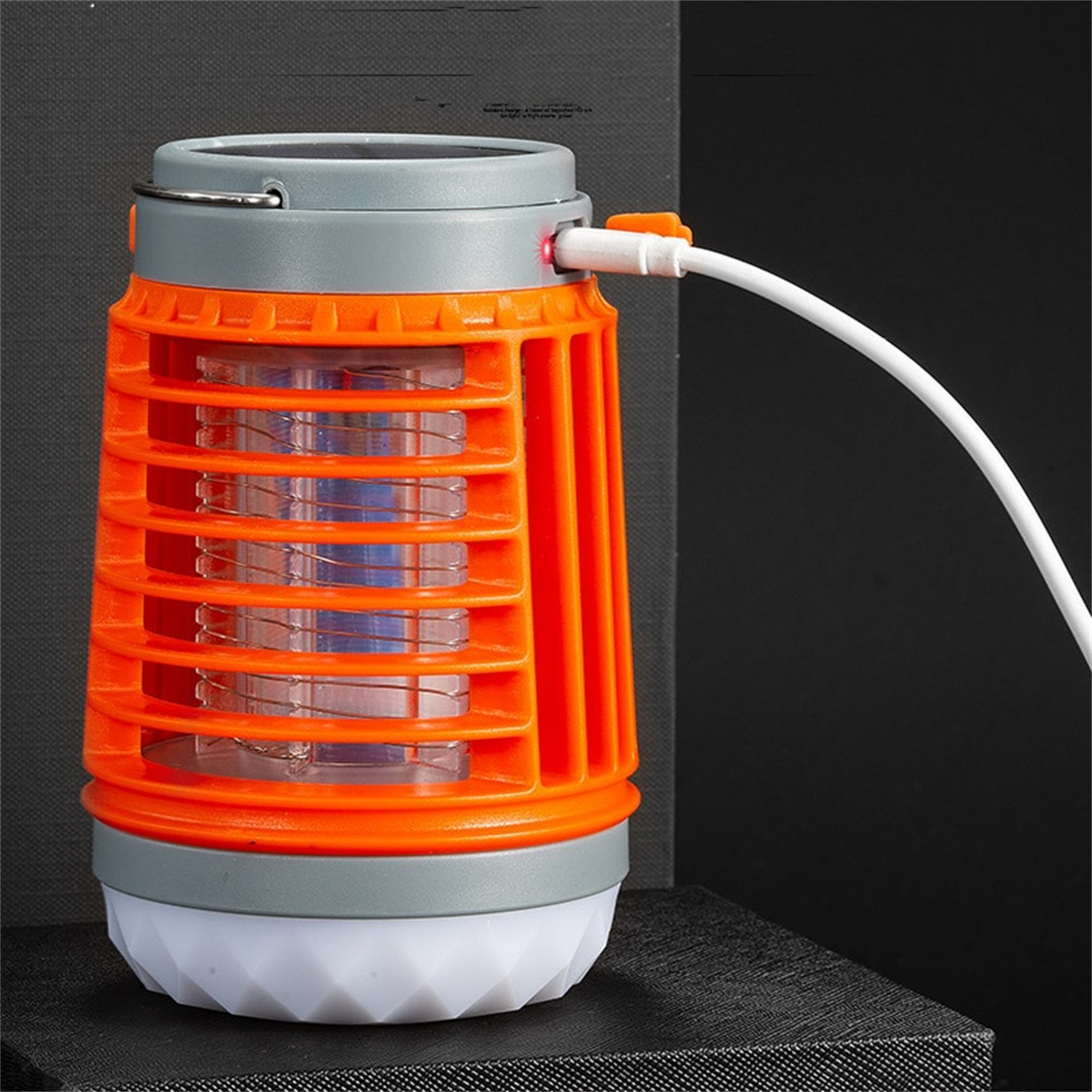 Orange und graue Moskitolampe mit weißem Ladekabel.