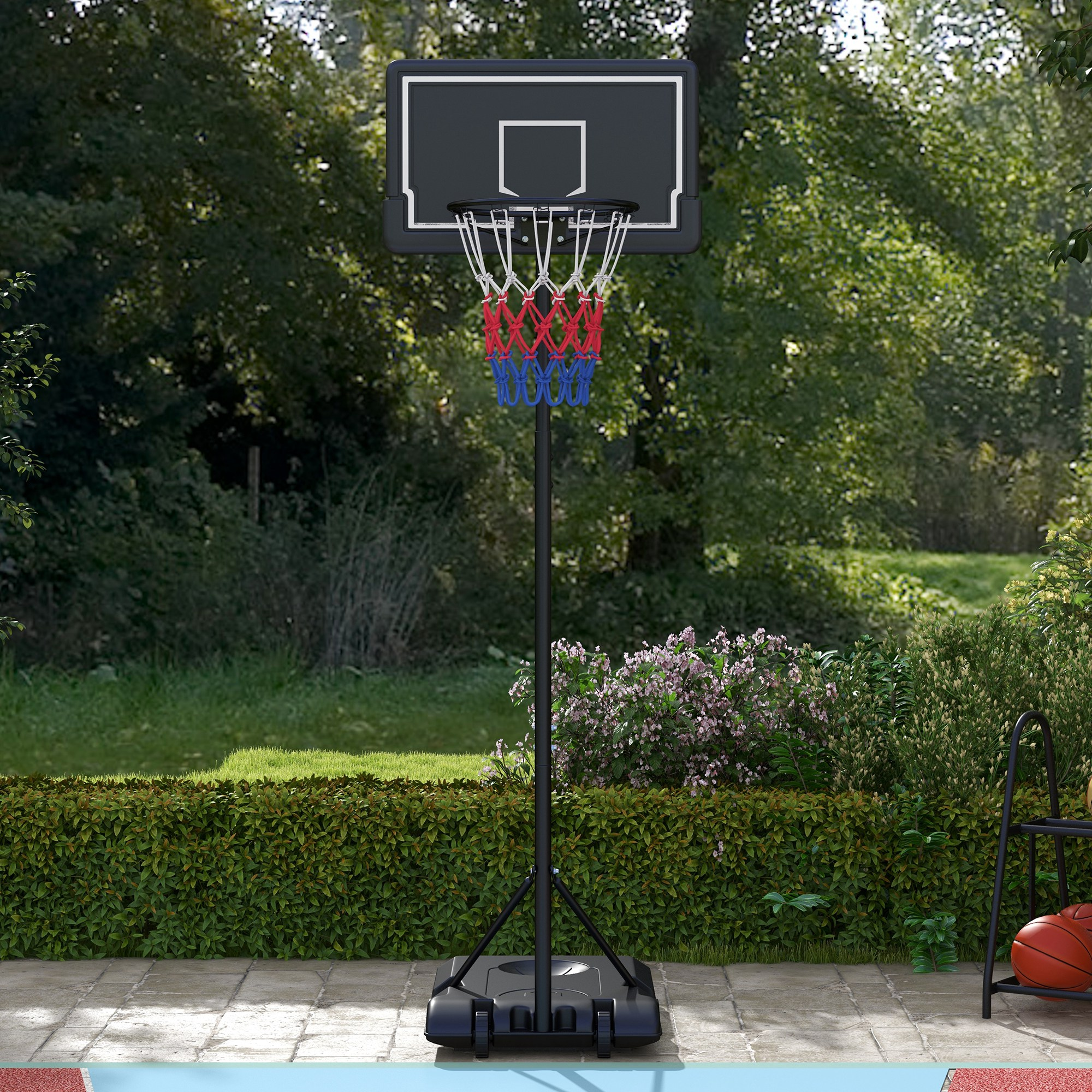 Basketballkorb mit blau-rotem Netz auf grünem Rasen mit buschigem Hintergrund.