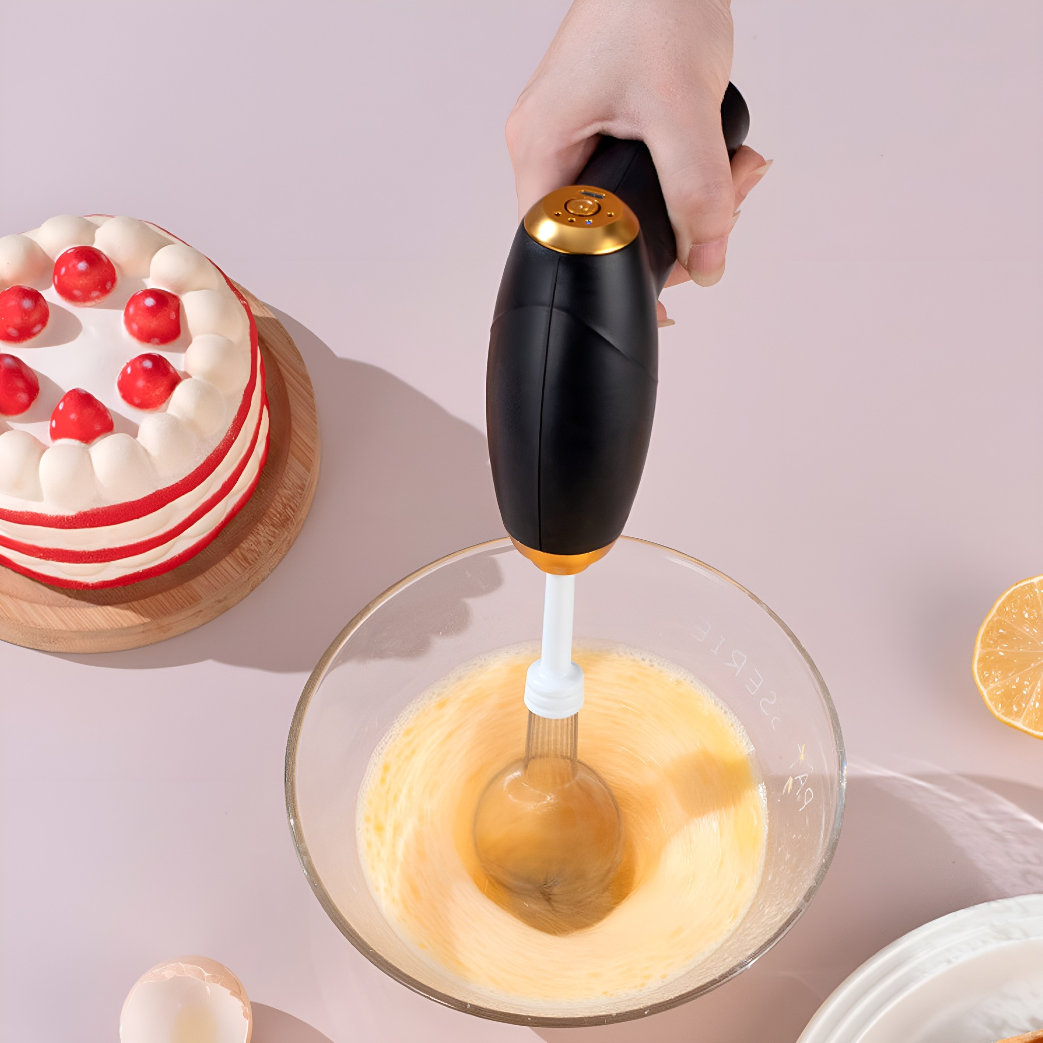 Eine Hand, die einen elektrischen Mixer über einer Schüssel mit Eiern hält. Im Hintergrund steht ein Kuchen.