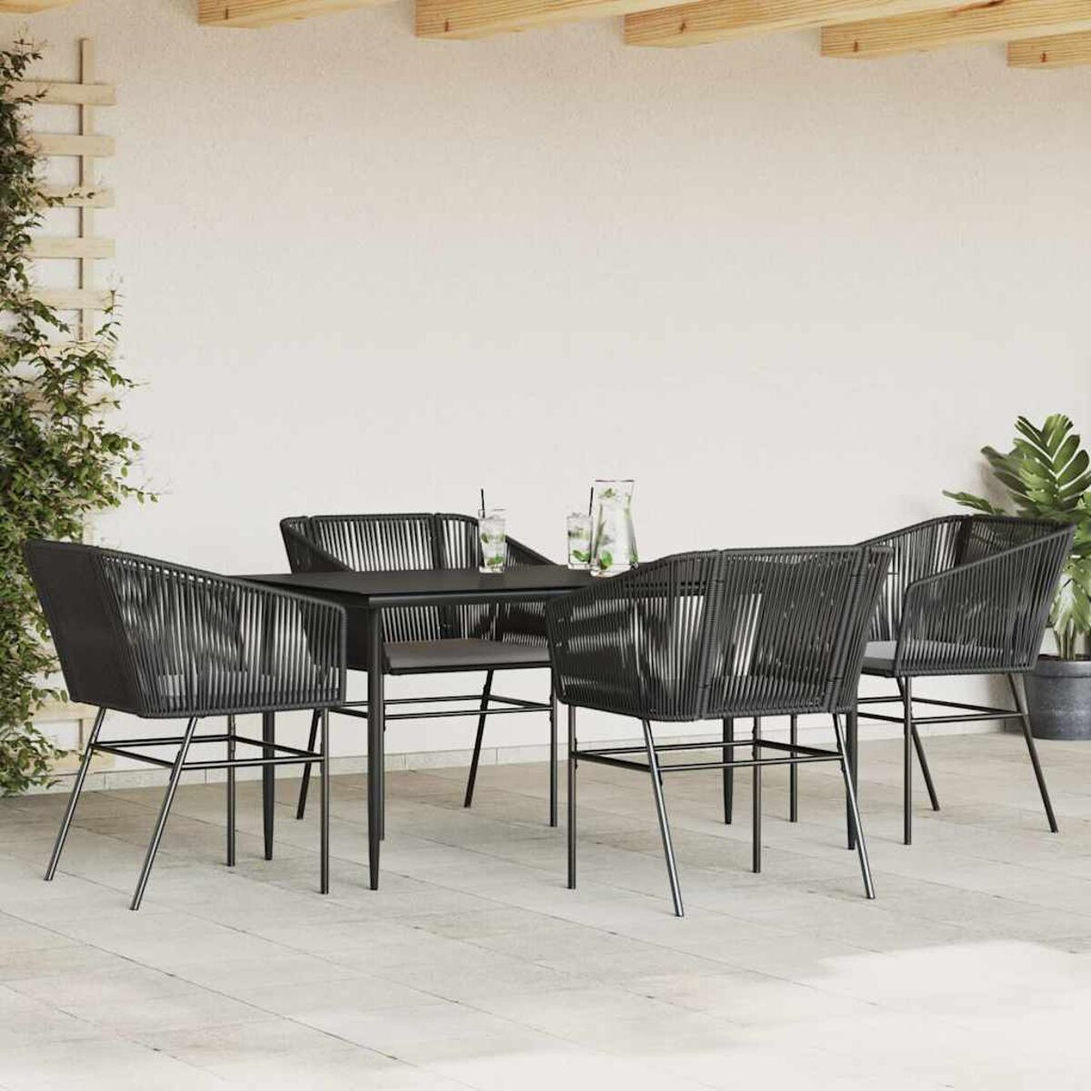 Set da pranzo all'aperto con tavolo nero, quattro sedie e bevande.