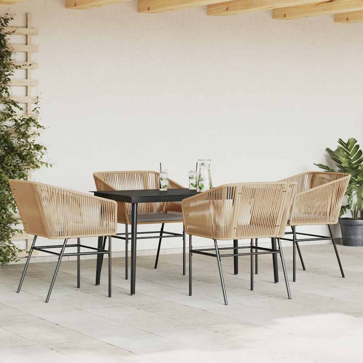 Set da pranzo all'aperto con sedie color cuoio e tavolo nero. Con piante e muro bianco.