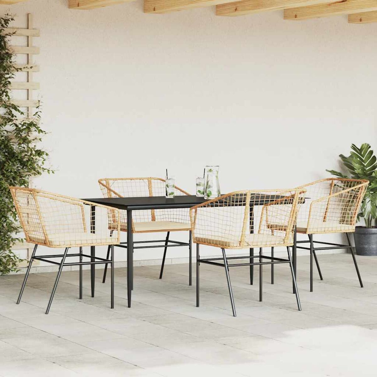 Set da patio esterno con tavolo nero, quattro sedie e piante. Sedie in rattan intrecciato.