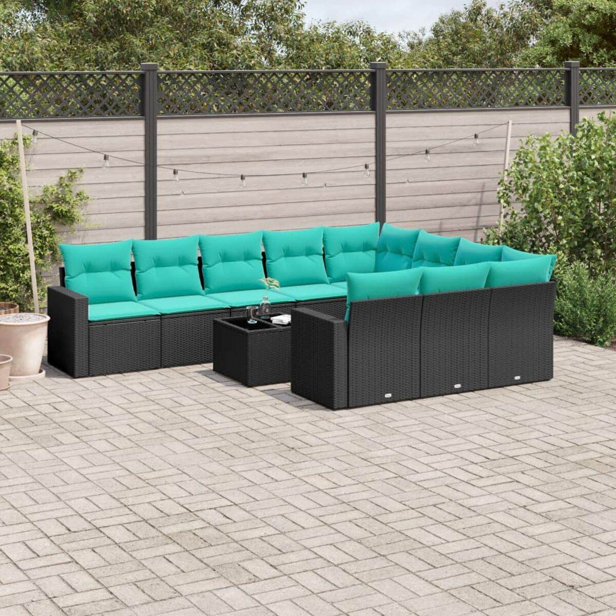 Set di mobili da patio esterno, telaio nero, con cuscini turchesi, su un patio in mattoni.