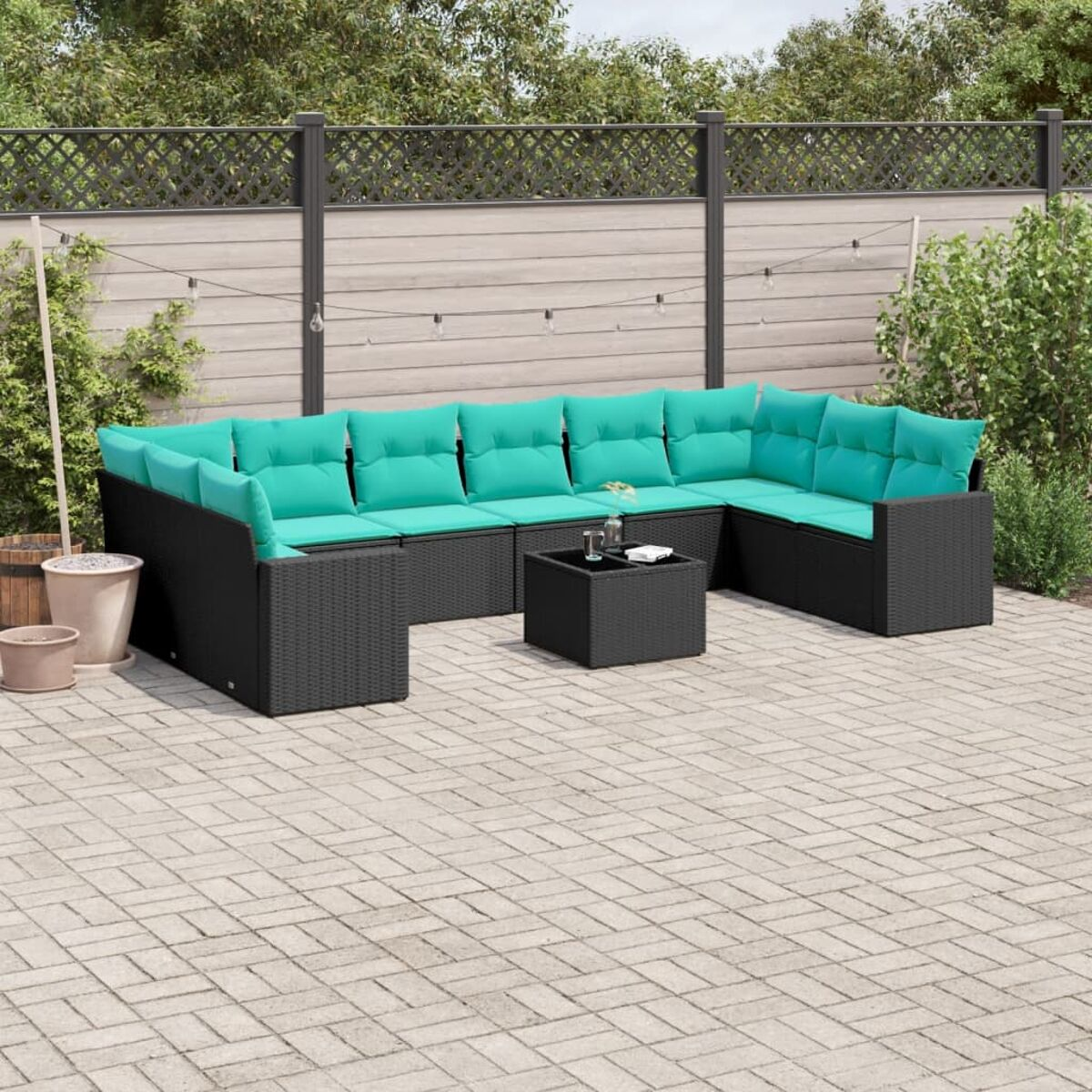 Outdoor-Ecksofa mit türkisfarbenen Kissen und einem Tisch, auf einer Terrasse mit Zaun und Pflanzen.