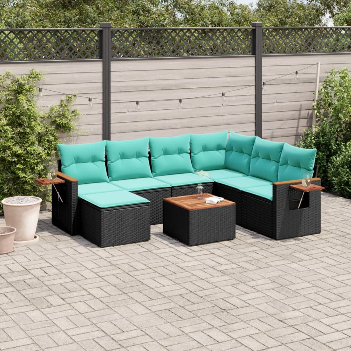 Un divano componibile in vimini nero per esterni con cuscini verde acqua, un tavolino in legno e un'ambientazione patio.