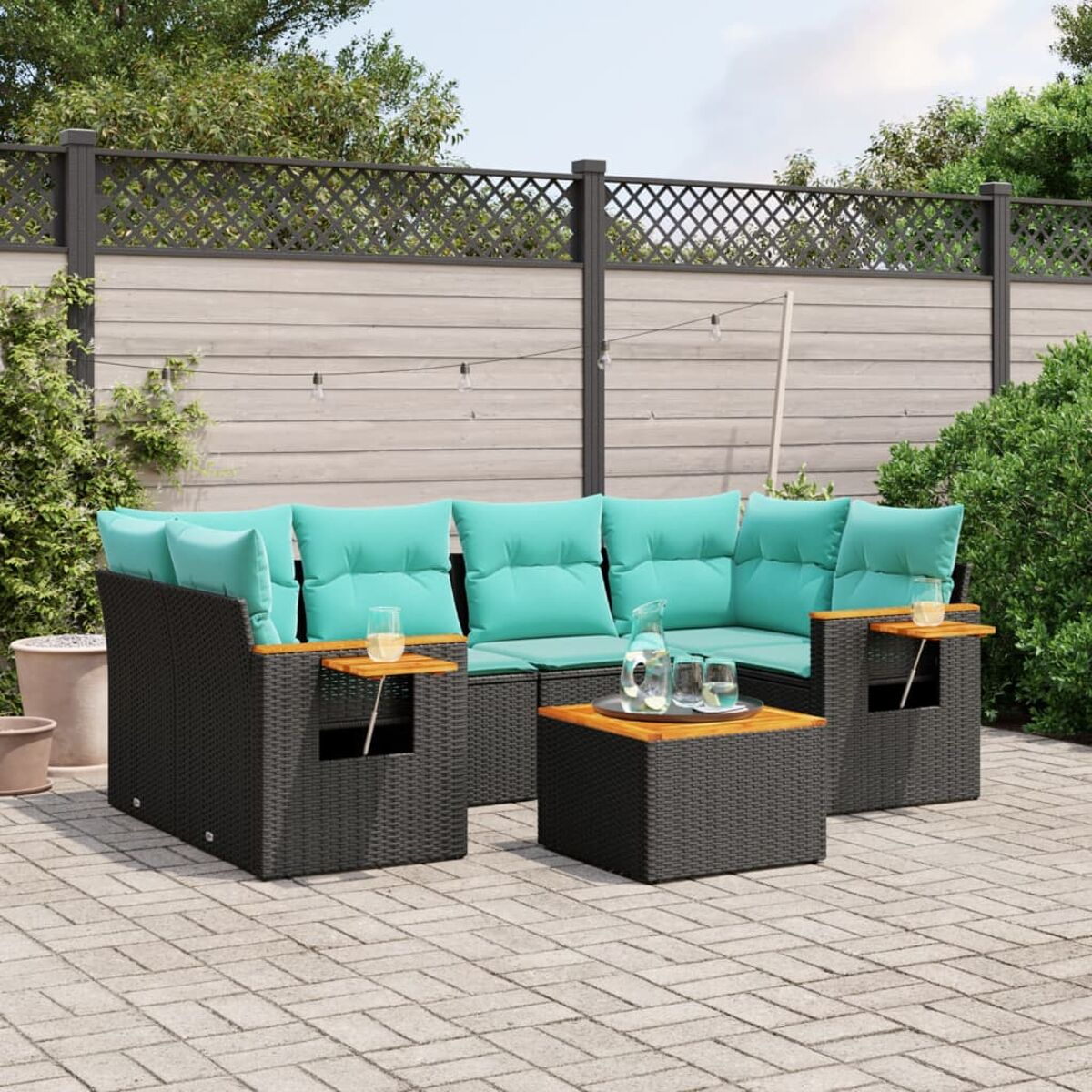 Set di mobili da esterno su un patio. Set in rattan nero con cuscini turchese e tavoli in legno.