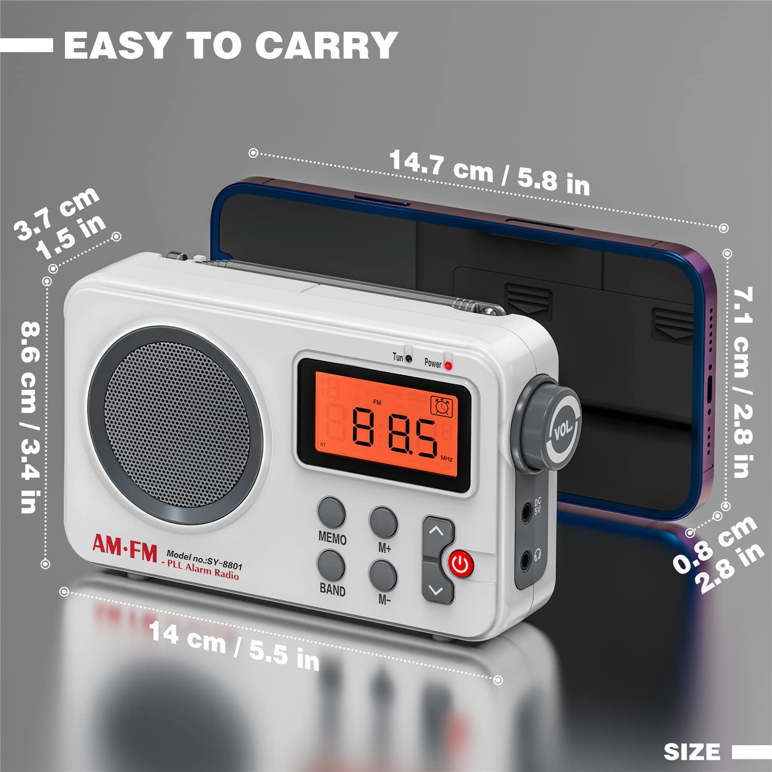Weißes tragbares AM/FM-Radio mit Digitalanzeige, Knöpfen und Abmessungen neben einem Telefon.