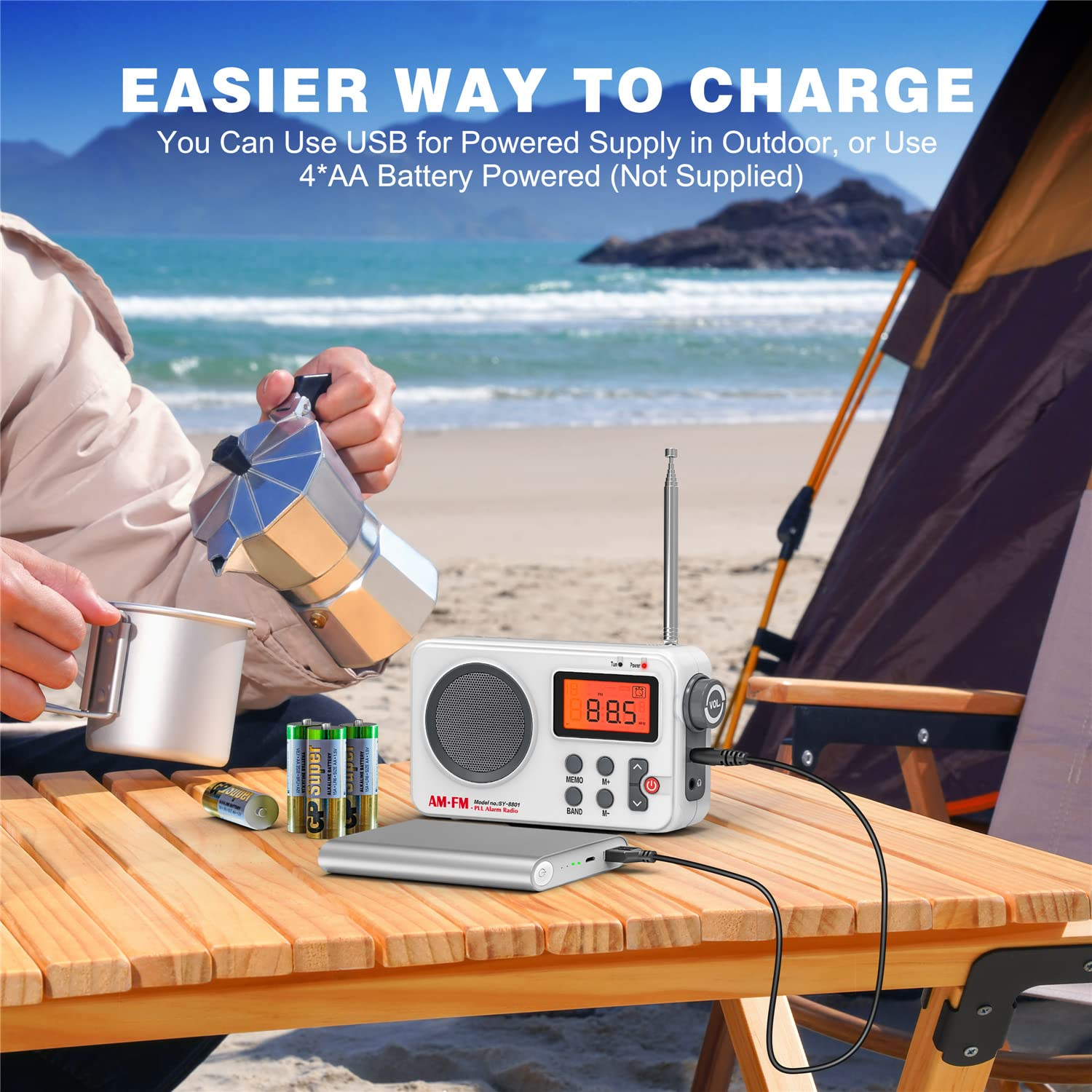 Eine Person, die ein weißes Radio mit einer Powerbank auflädt. Weitere Artikel: Batterien, eine Tasse und ein Camping-Setup auf einem Tisch.