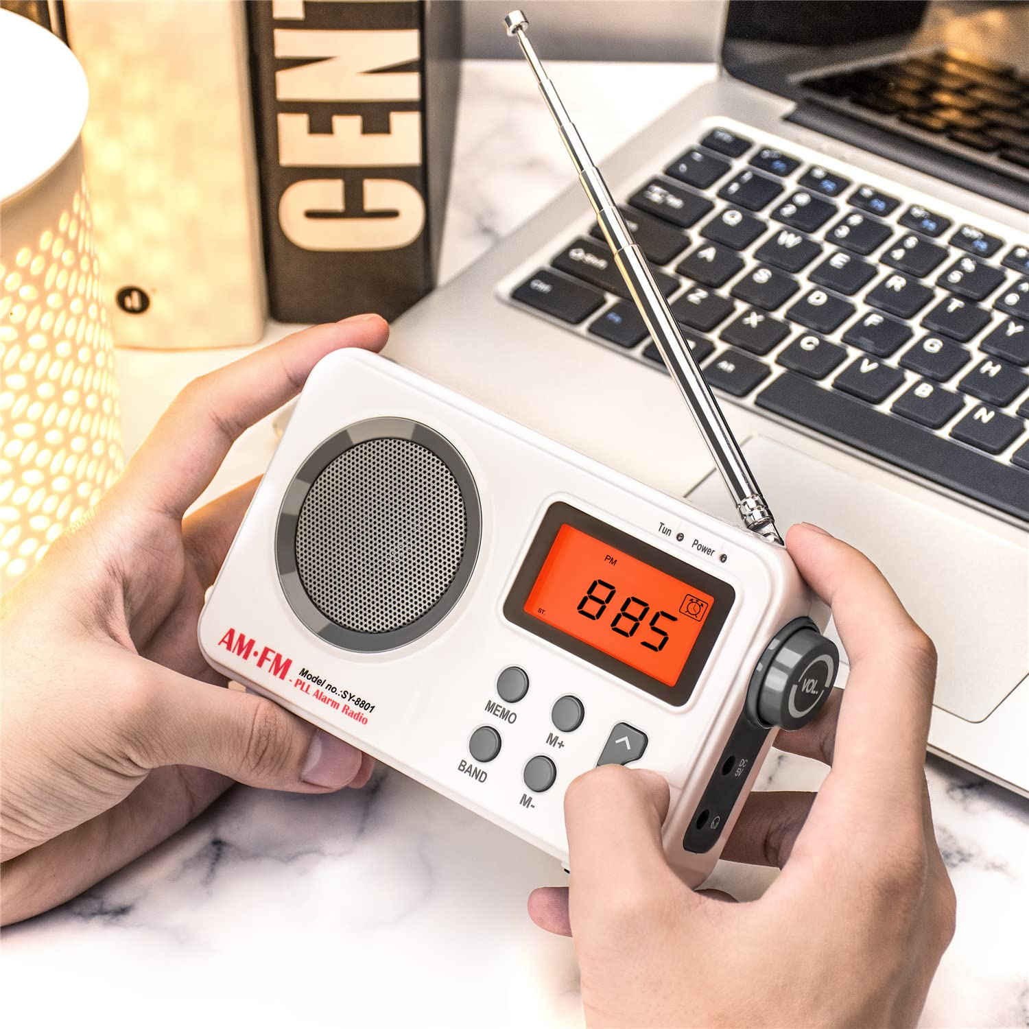 Hände halten ein weißes AM-FM-Radio. Das Radio hat ein Display, das 88,5 und verschiedene Tasten anzeigt.