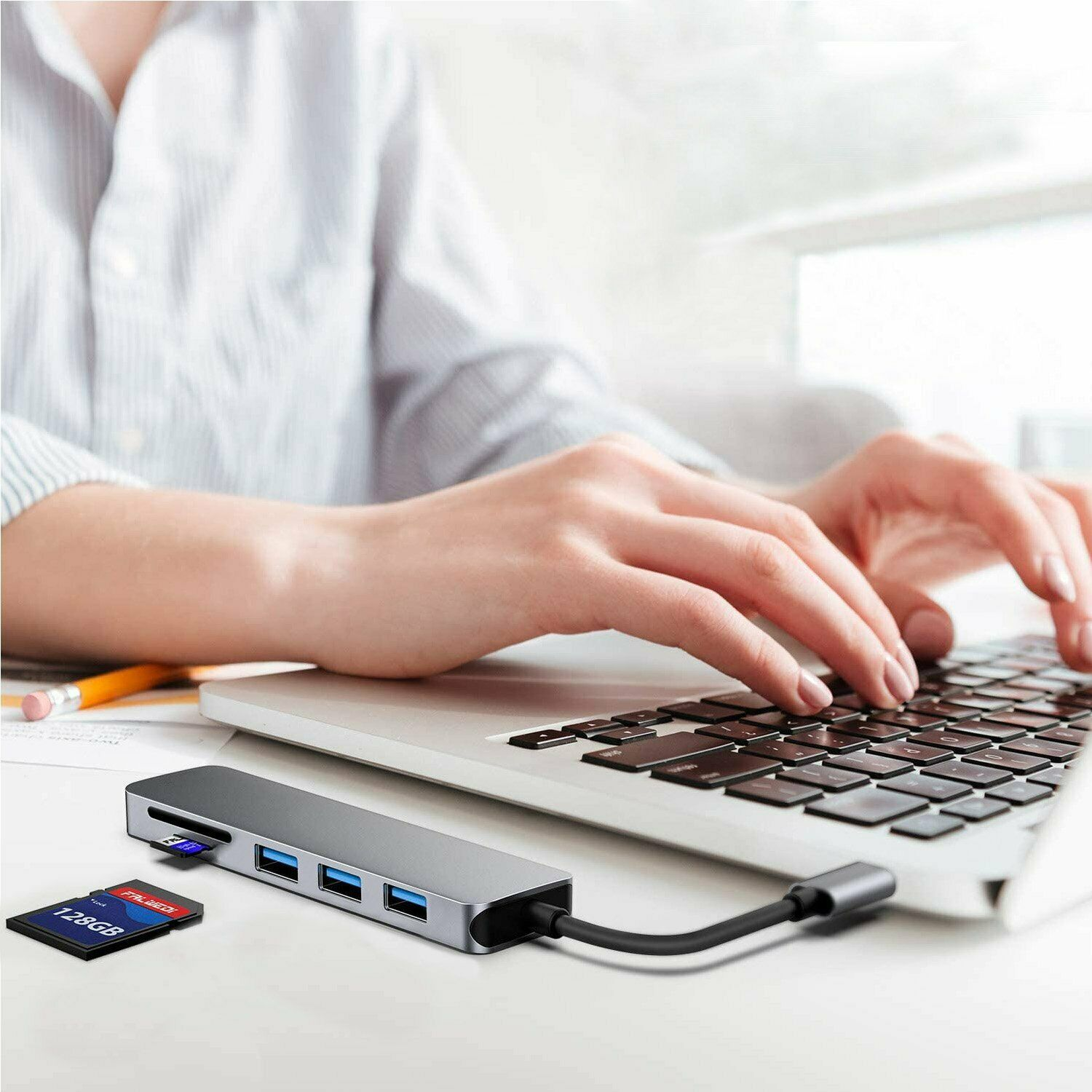Eine Person, die einen USB-Hub mit einem Laptop verwendet. Eine SD-Karte und ein USB-Laufwerk sind ebenfalls angeschlossen.