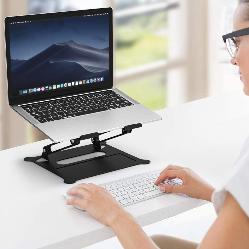 Frau benutzt Laptop auf schwarzem Ständer. Laptop geöffnet, mit Tastatur und Maus.