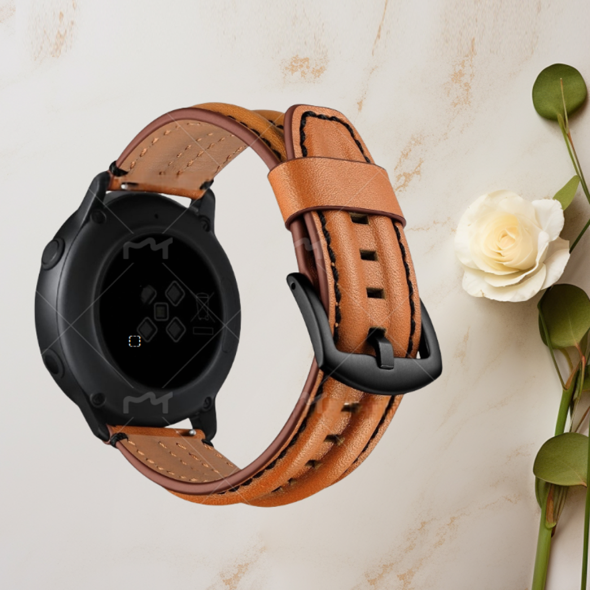 Orologio con cinturino in pelle marrone e fibbia nera. Fiore bianco e foglie verdi sullo sfondo.