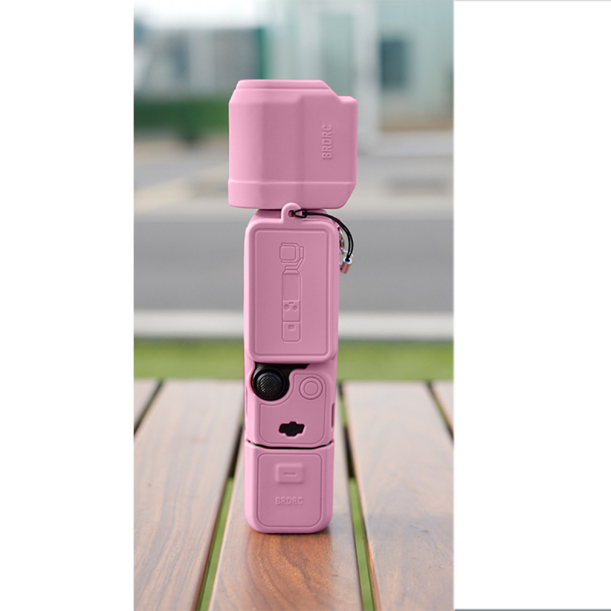 Pila di accessori per fotocamera rosa. Contiene vari componenti. Tavolo di legno.