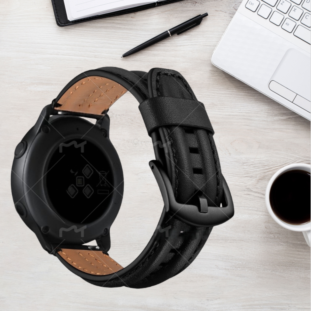 Smartwatch nero con cinturino in pelle, su una scrivania di legno con penna, caffè e laptop.