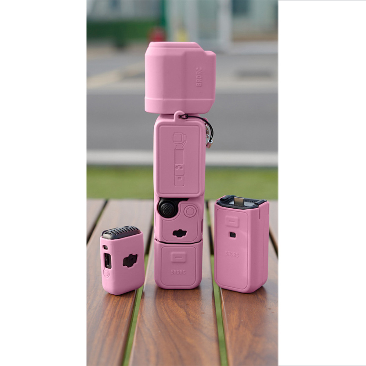 Rosa Action-Kamera-Set auf einem Holztisch. Enthält eine Hauptkamera und zwei zusätzliche Module.