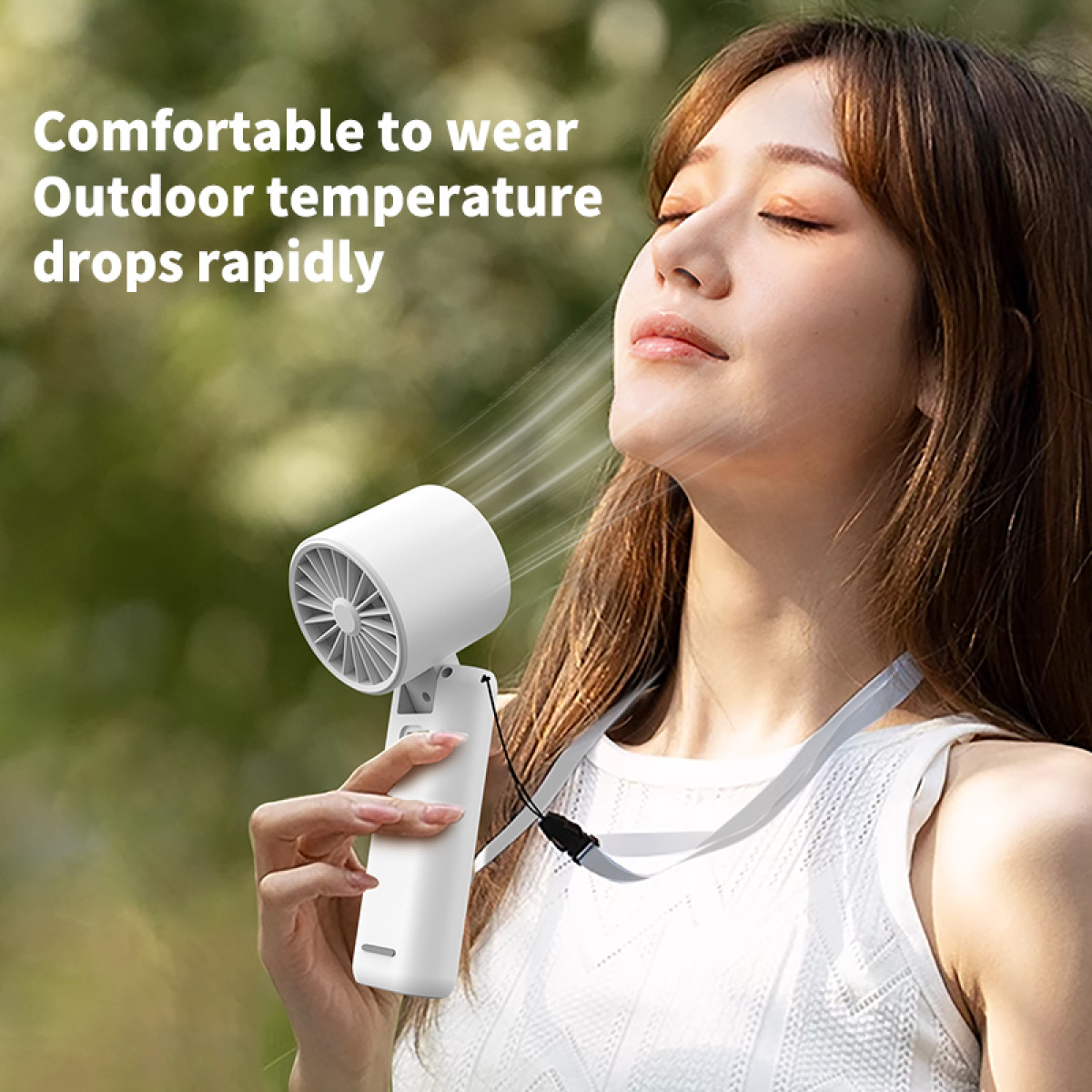 A woman with a white portable fan around her neck. She is outside in the sunshine.