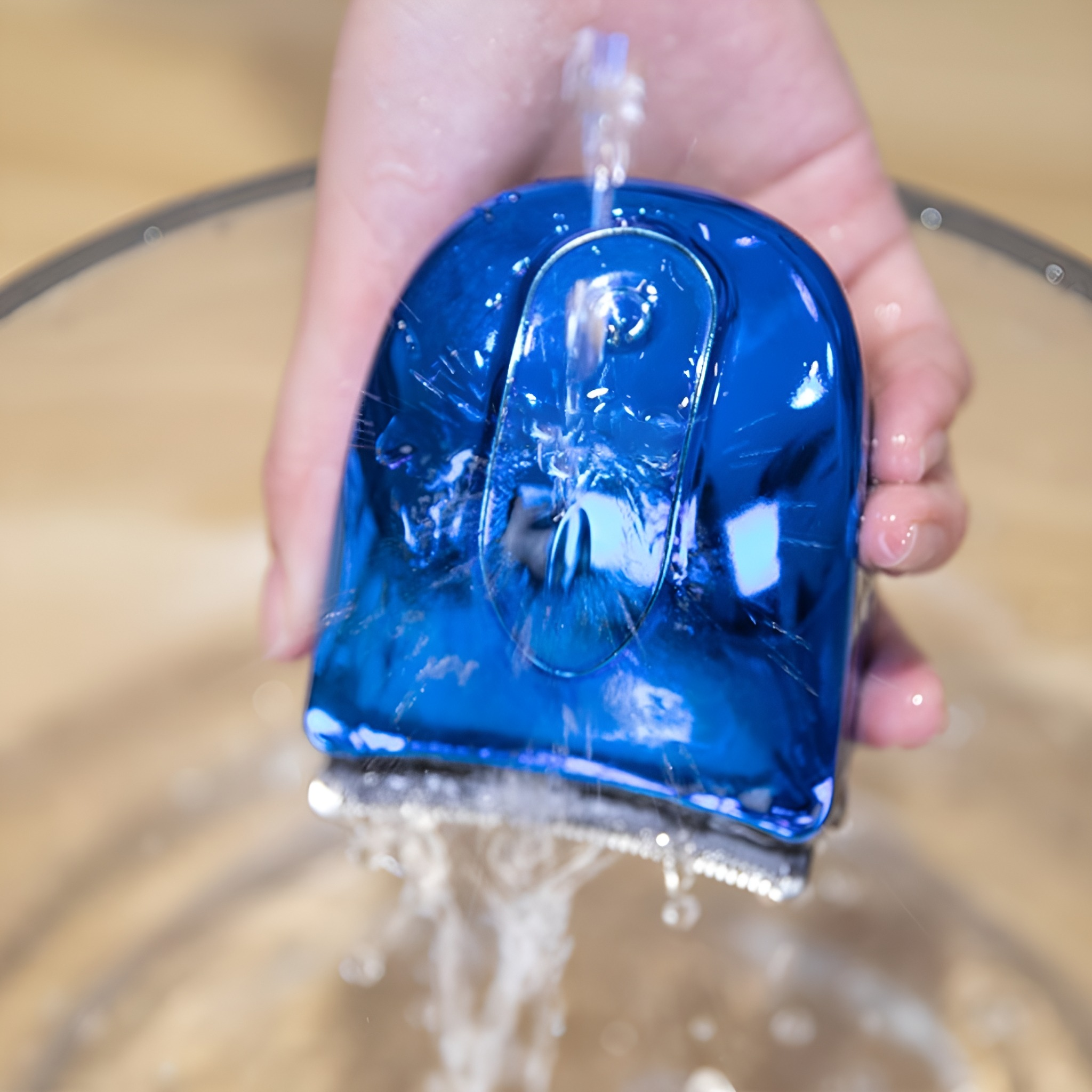 Hand wäscht einen blauen Haarschneider in einer Glasschüssel mit Wasser. Nahaufnahme.