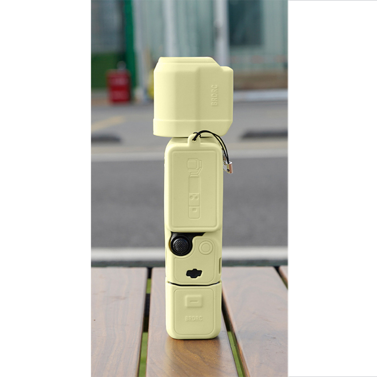 Una pila di tre sezioni di un dispositivo giallo chiaro simile a una fotocamera con un cinturino nero.