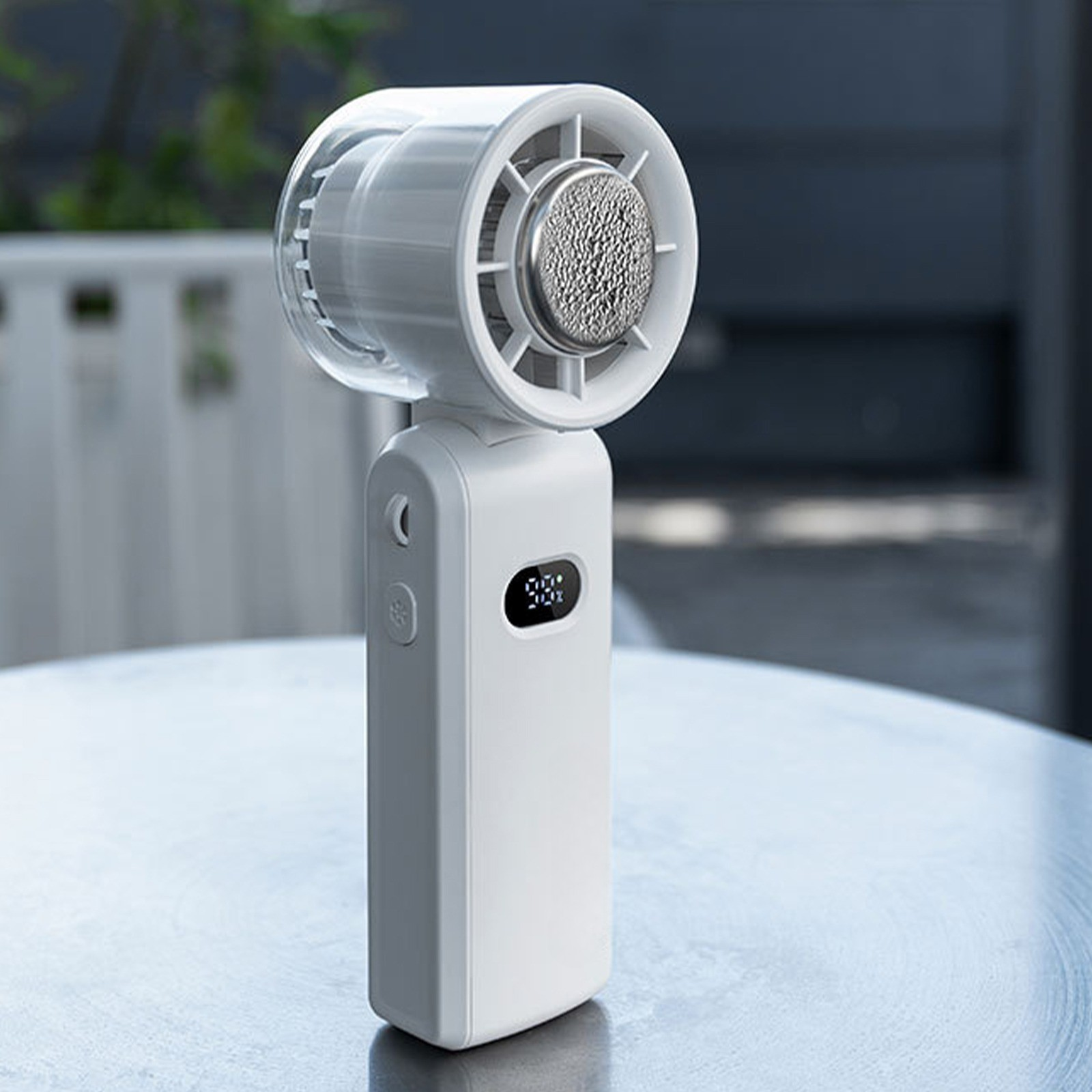 Ein weißer Handventilator mit digitaler Anzeige und silbernem Netz.