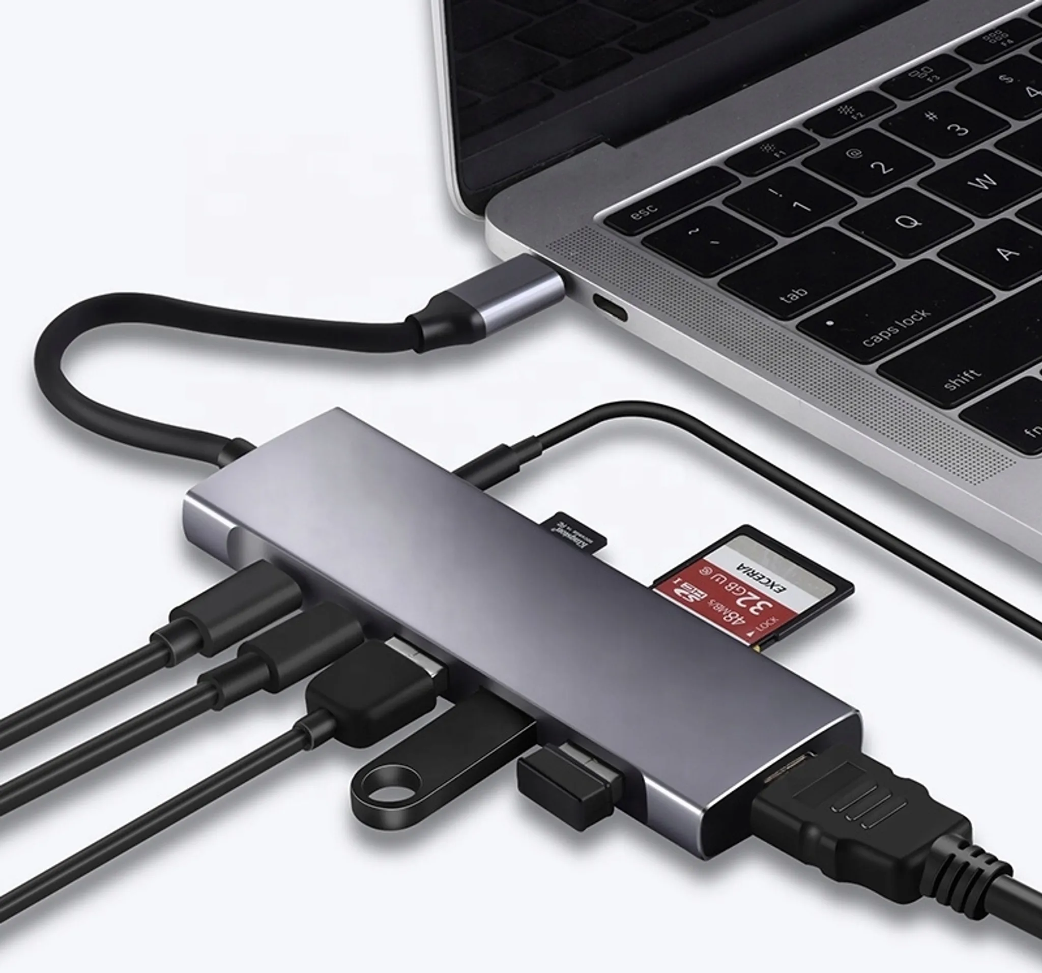 Silberner Hub mit USB-Anschlüssen, SD-Karte und HDMI, verbunden mit Laptop.