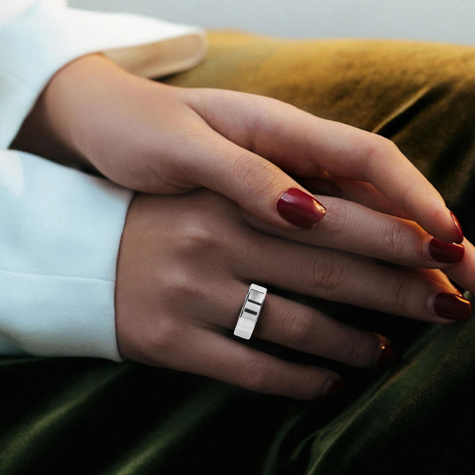 Hände mit roten Nägeln halten einen silbernen Ring mit schwarz-weißen Streifen.
