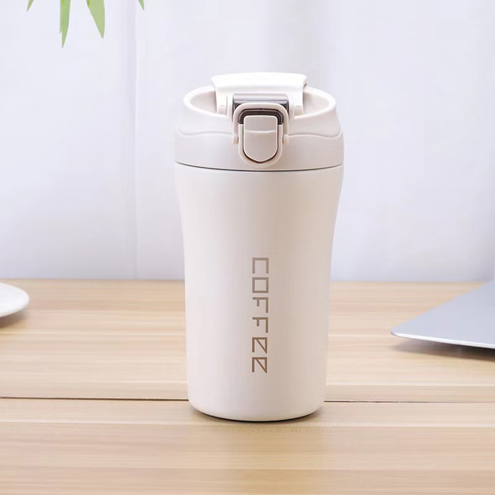 Ein cremefarbener Reisebecher mit dem vertikal aufgedruckten Wort 'COFFEE'.