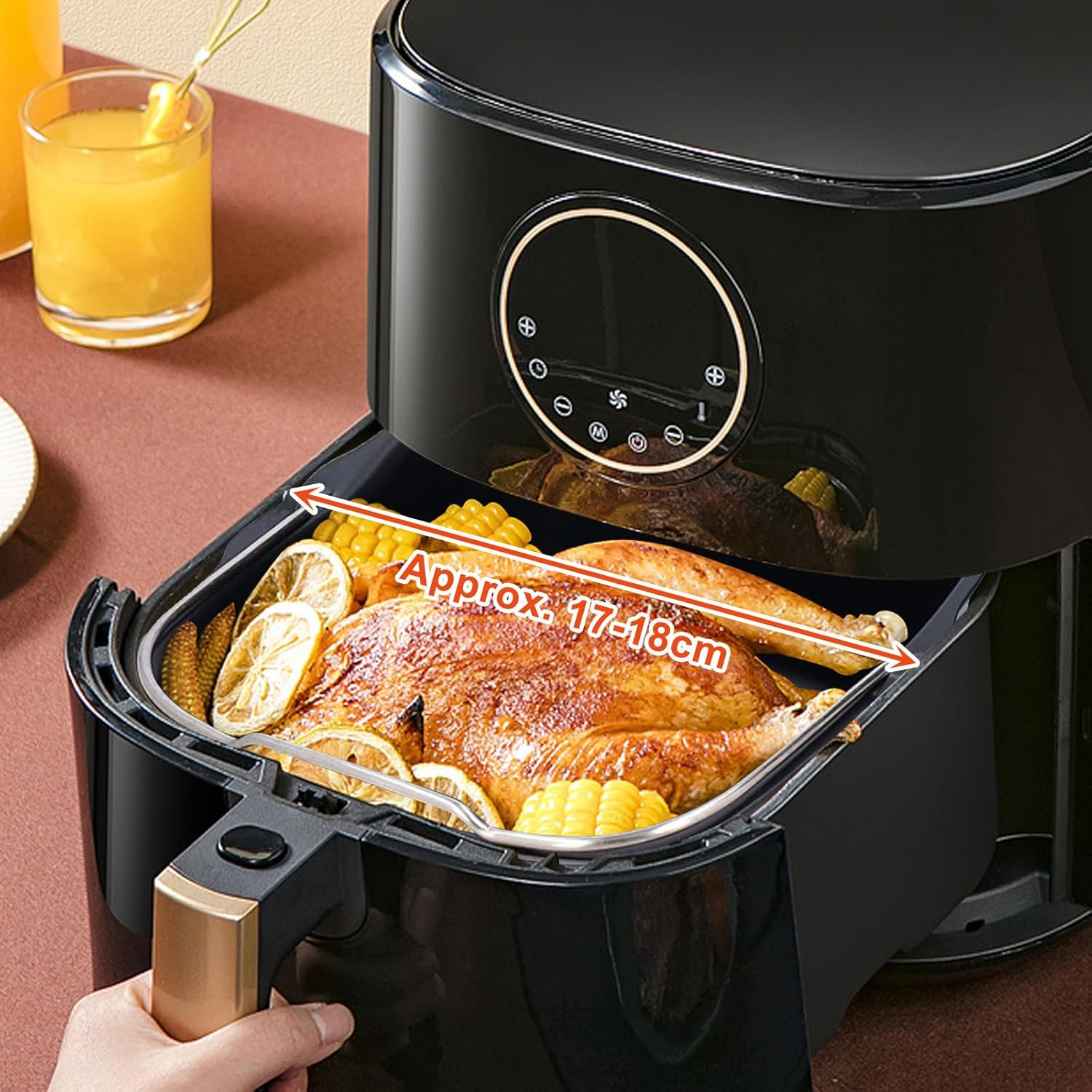 Eine Heißluftfritteuse mit einem gekochten Huhn, Zitronen und Mais.