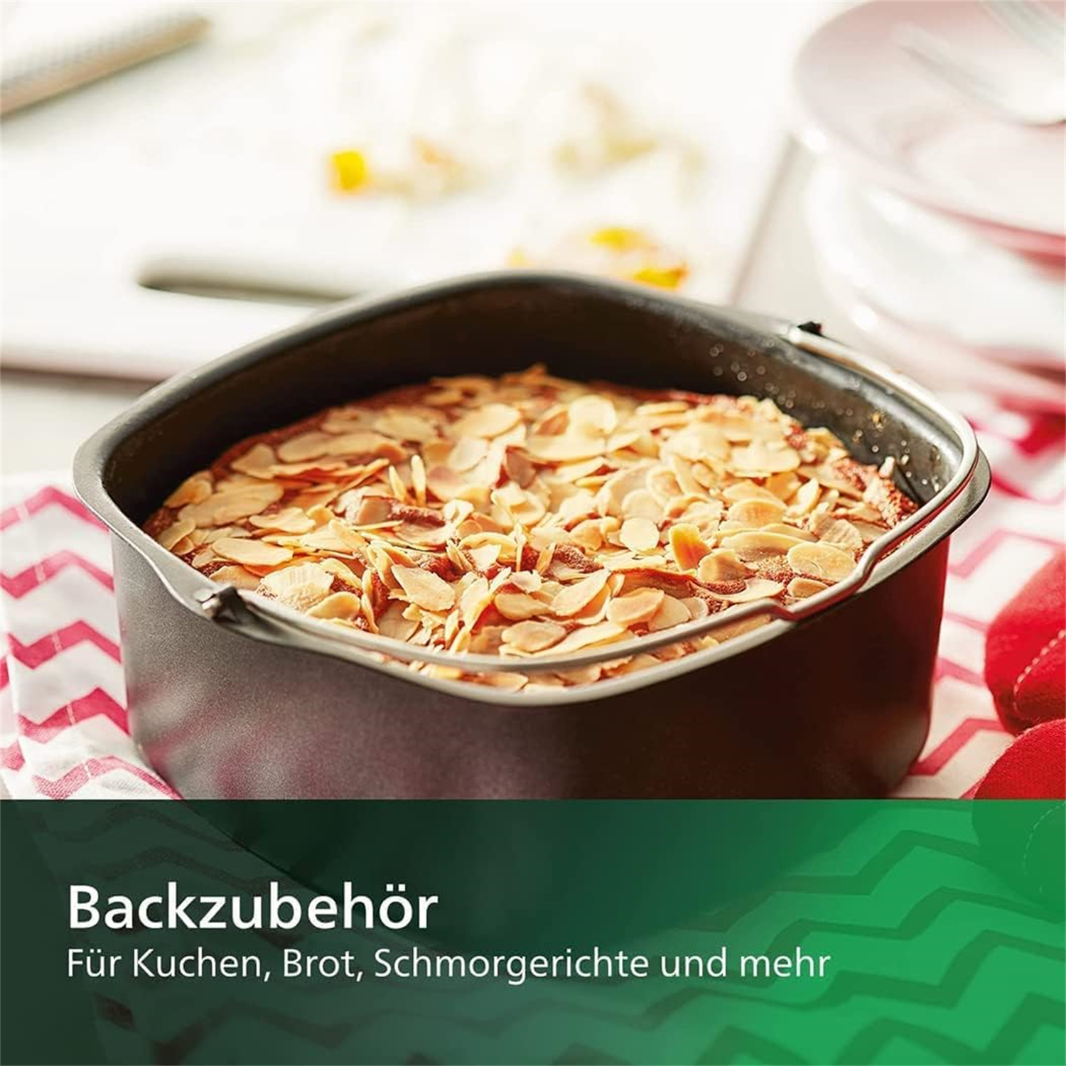 Kuchen in einer Backform mit Mandelblättchen. Grüner Text unten, weiße Oberfläche.