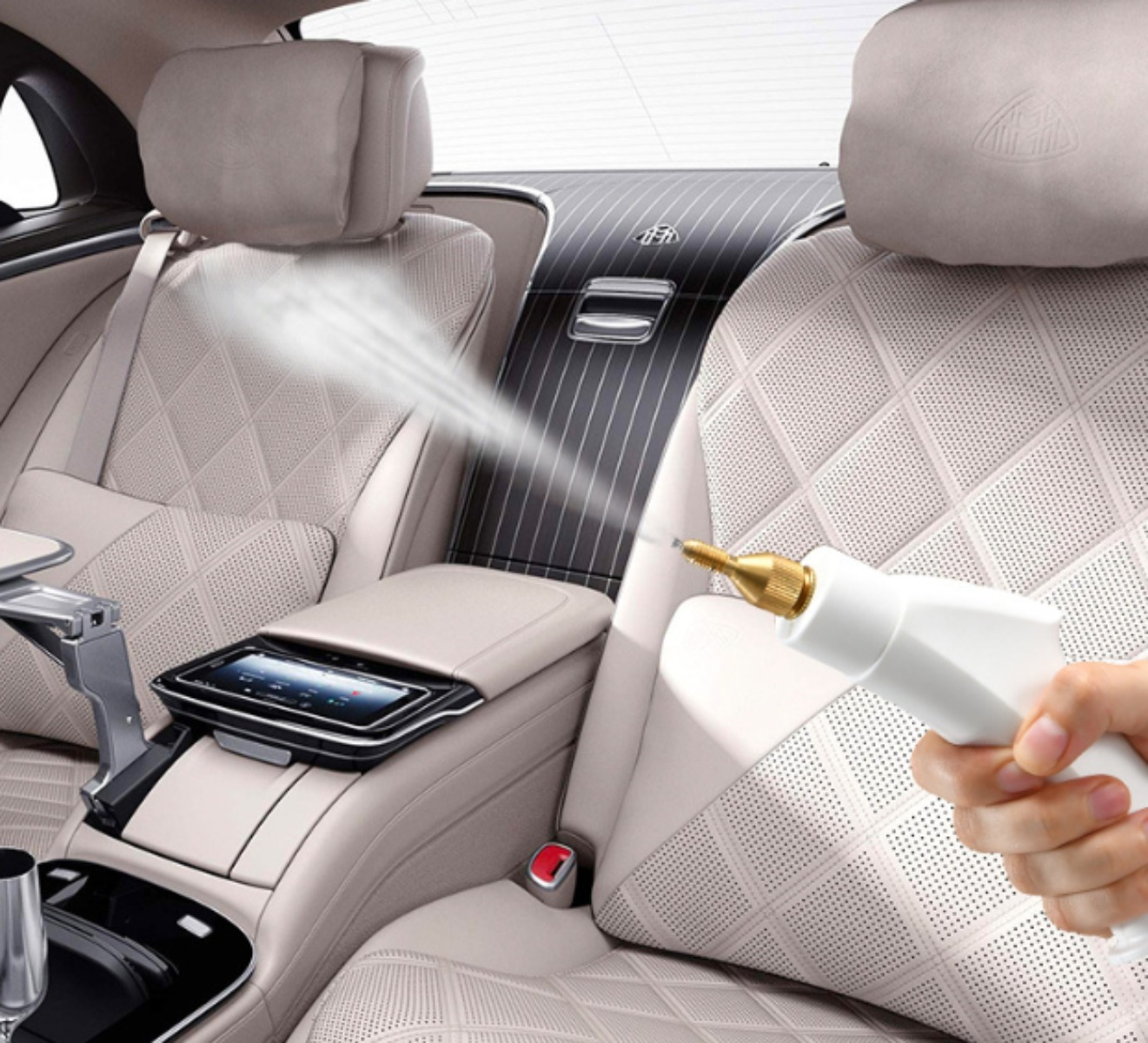 Eine weiße Reinigungspistole, die Nebel in einem Auto mit beigen Ledersitzen versprüht.