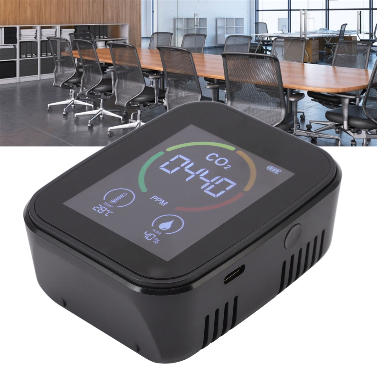 Schwarzer CO2-Monitor mit Anzeige von PPM, Temperatur und Luftfeuchtigkeit, in einer Besprechungsraumumgebung.