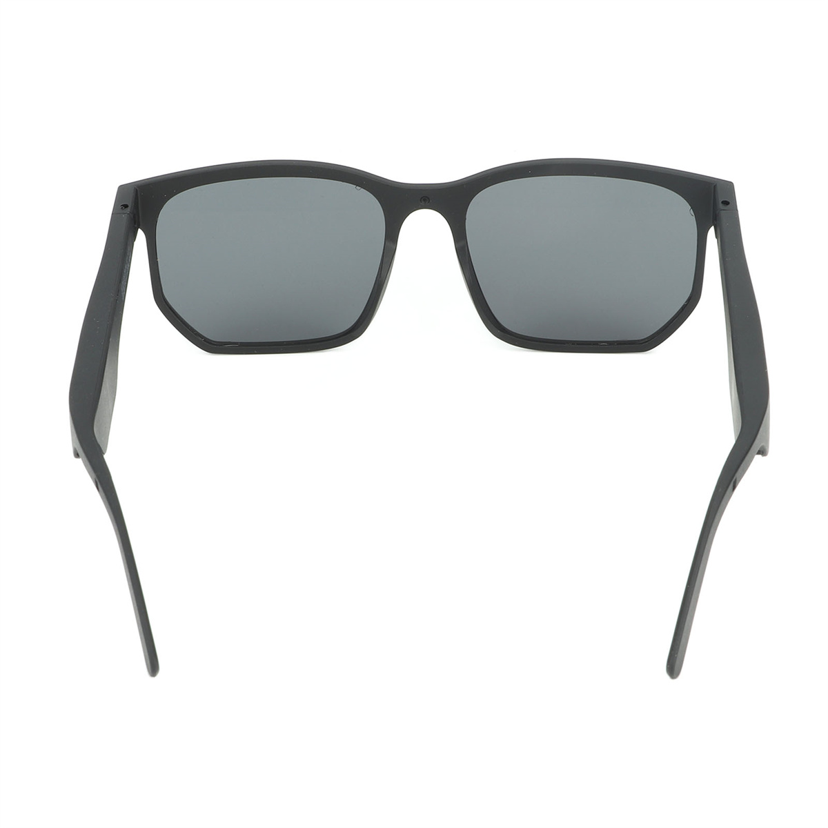 Schwarze Sonnenbrille mit grauen Gläsern. Sie haben ein modernes Design und liegen auf einer weißen Oberfläche.