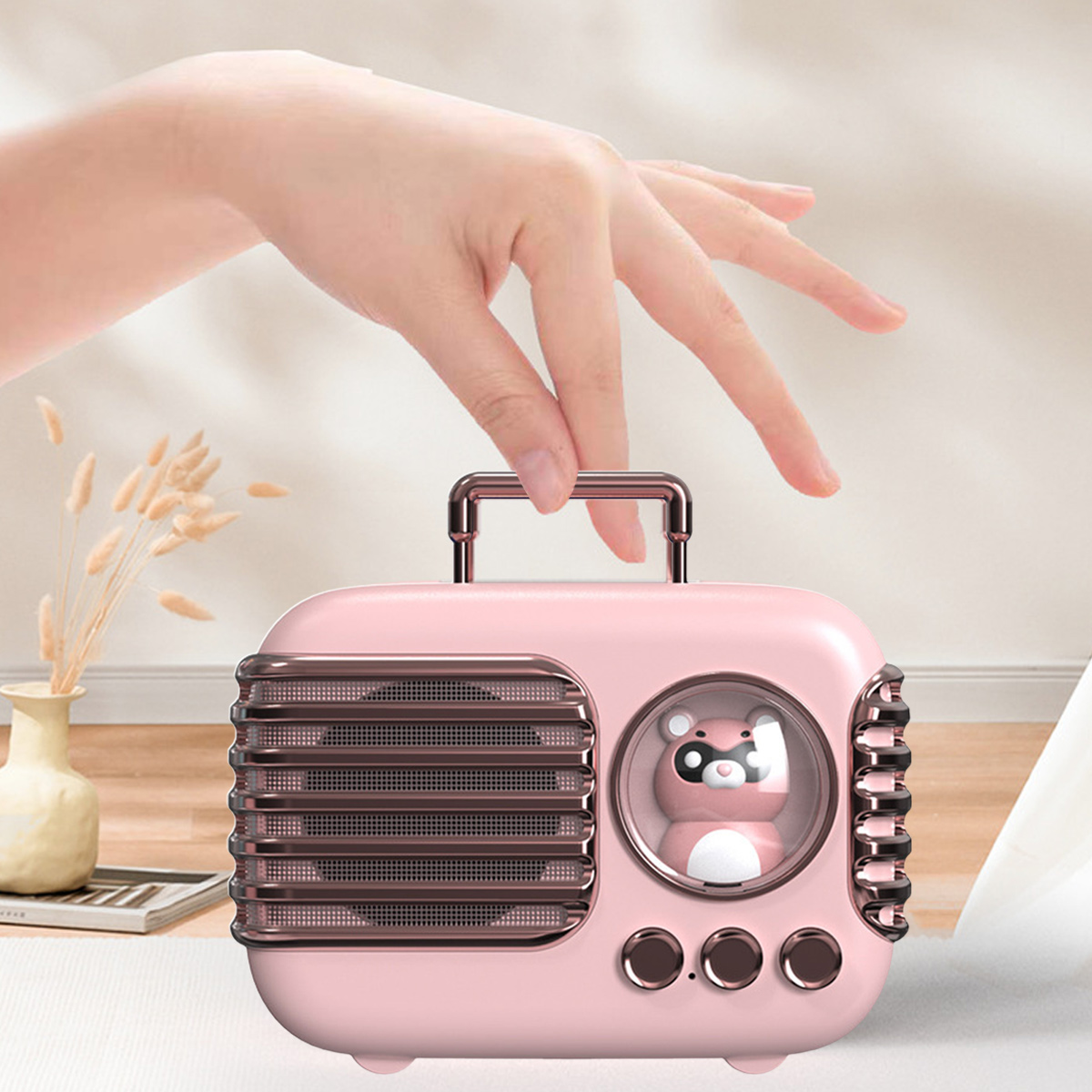 Rosa Lautsprecher im Retro-Radio-Stil mit einer Bärenfigur. Eine Hand greift danach.