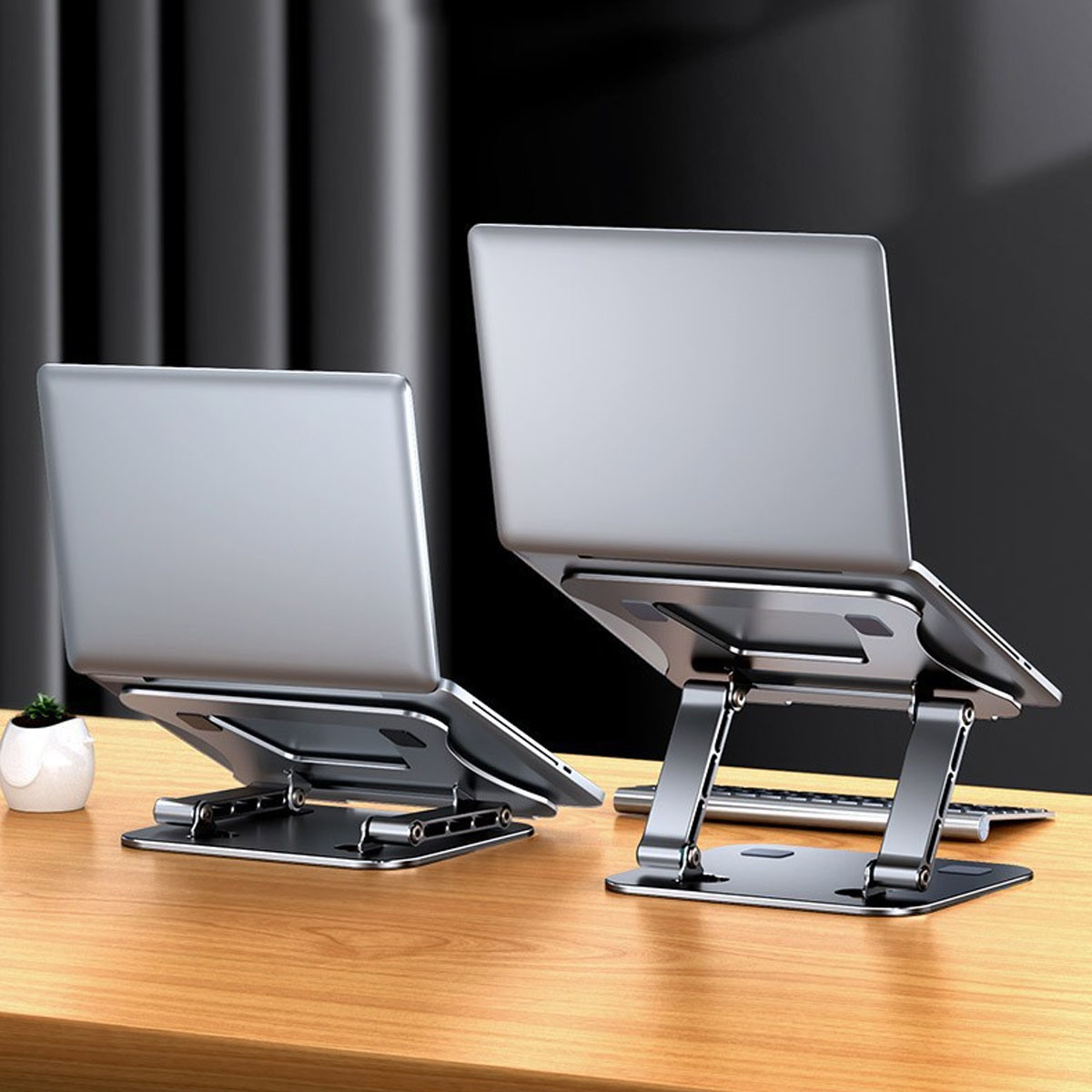 Zwei silberne Laptopständer mit Laptops, auf einem Holztisch, schwarzer Hintergrund.