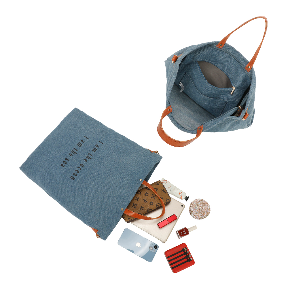 Bolso tote de mezclilla abierto con objetos que se derraman. Incluye bolso, maquillaje, teléfono y cosméticos.
