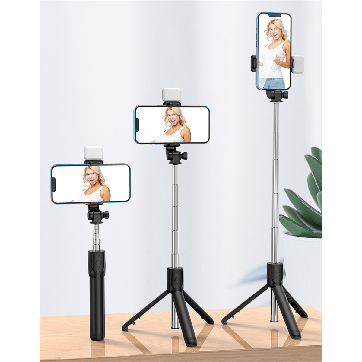 Drei Selfie-Sticks mit angebrachten Telefonen, vor hellem Hintergrund, Holztisch dargestellt.