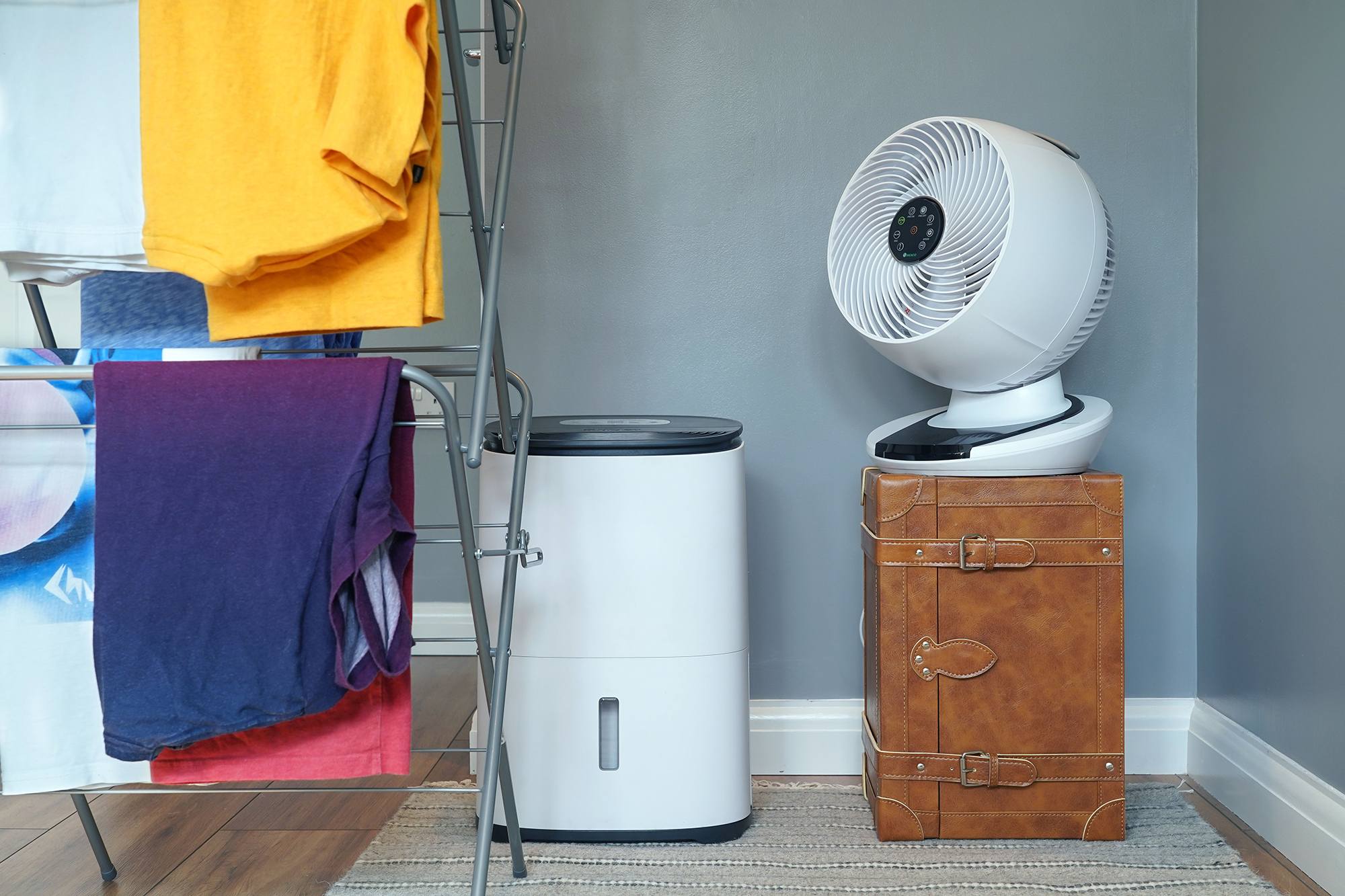 Wieszak na pranie z ubraniami, osuszaczem powietrza i wentylatorem na walizce.