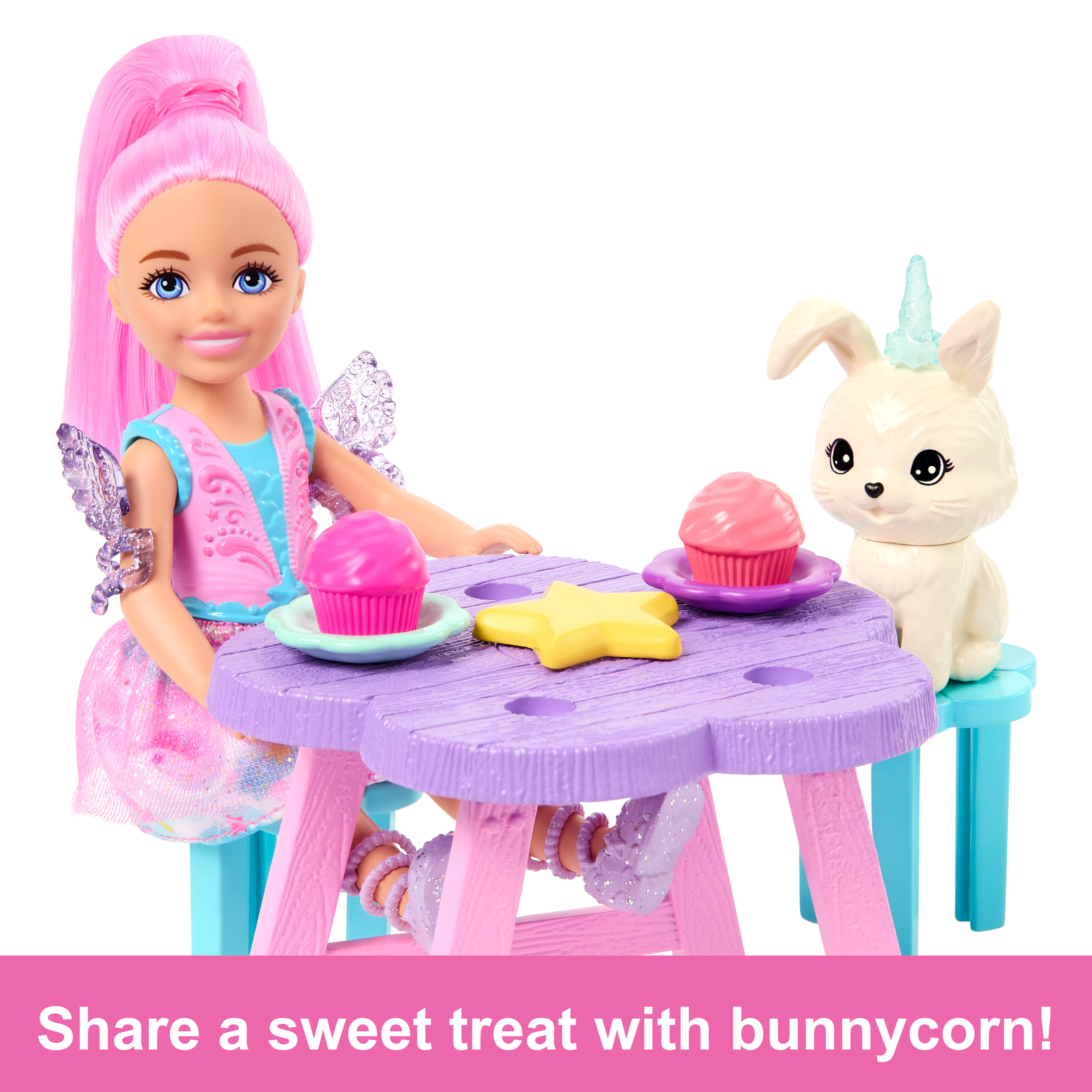 Una bambola e un bunnycorn a un tavolo con dolcetti, su sfondo bianco.