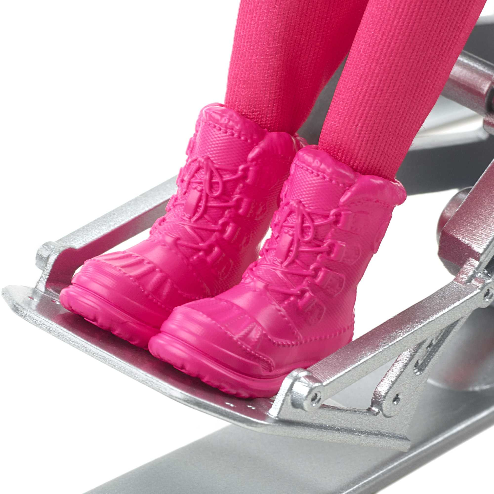 Nahaufnahme von rosa Stiefeln und rosa Leggings einer Puppe auf Skiern.