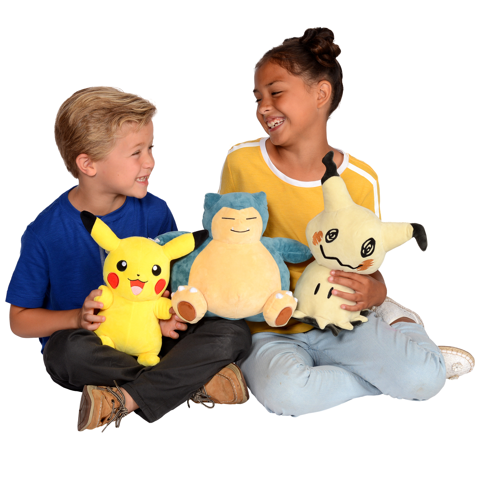 Zwei Kinder sitzen mit drei Plüschtieren: Pikachu, Snorlax und Mimikyu. Beide Kinder lächeln.