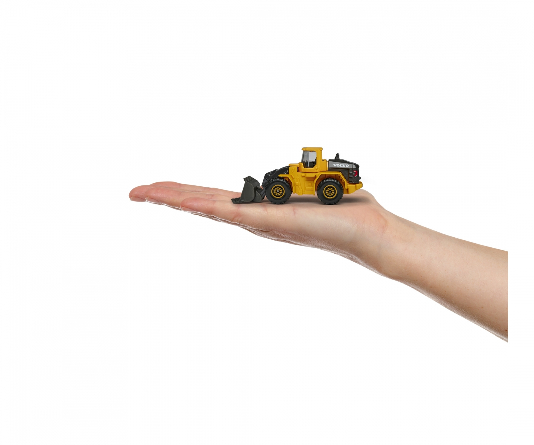 Żółta zabawka Volvo jest trzymana w dłoni na białym tle.
