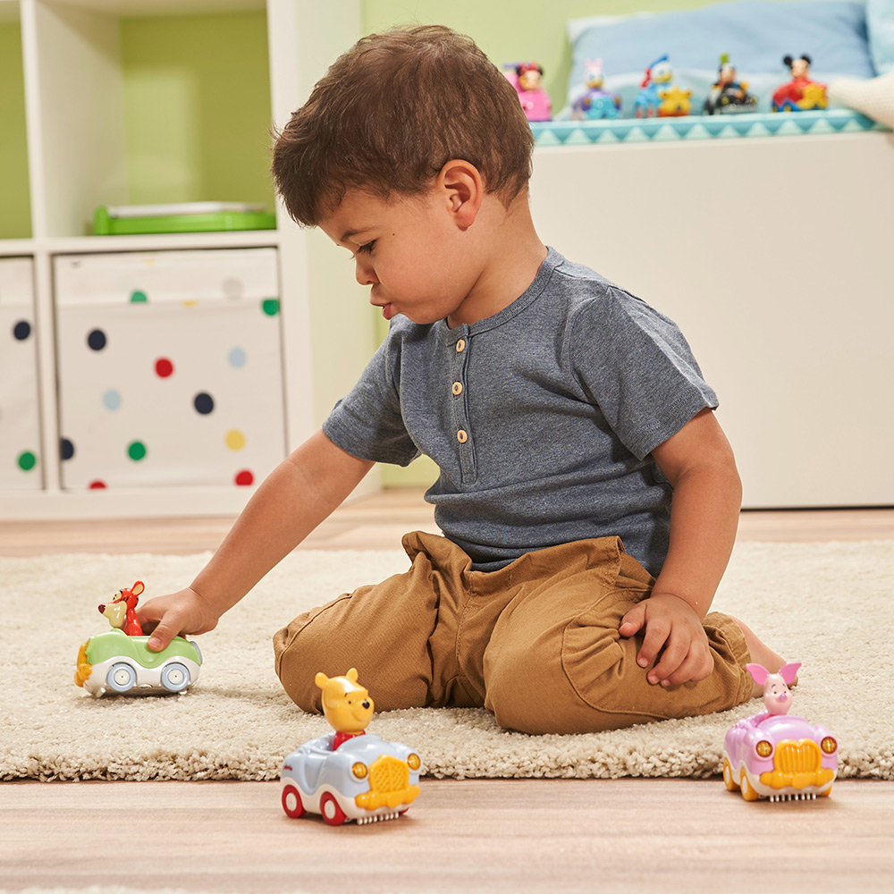 Ein kleiner Junge spielt mit Spielzeugautos. Es gibt vier Spielzeugautos mit Zeichentrickfiguren.