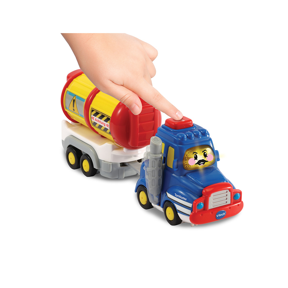 Eine Hand zeigt auf einen blau-gelben Spielzeug-Lkw mit angehängtem roten Tank, auf weißem Untergrund.