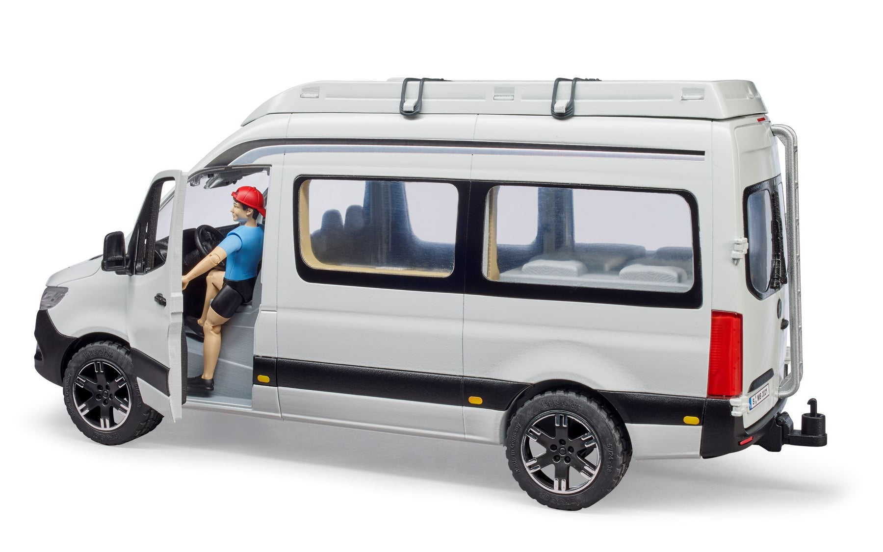 Zabawkowy biały kamper z osobą w otwartych drzwiach.