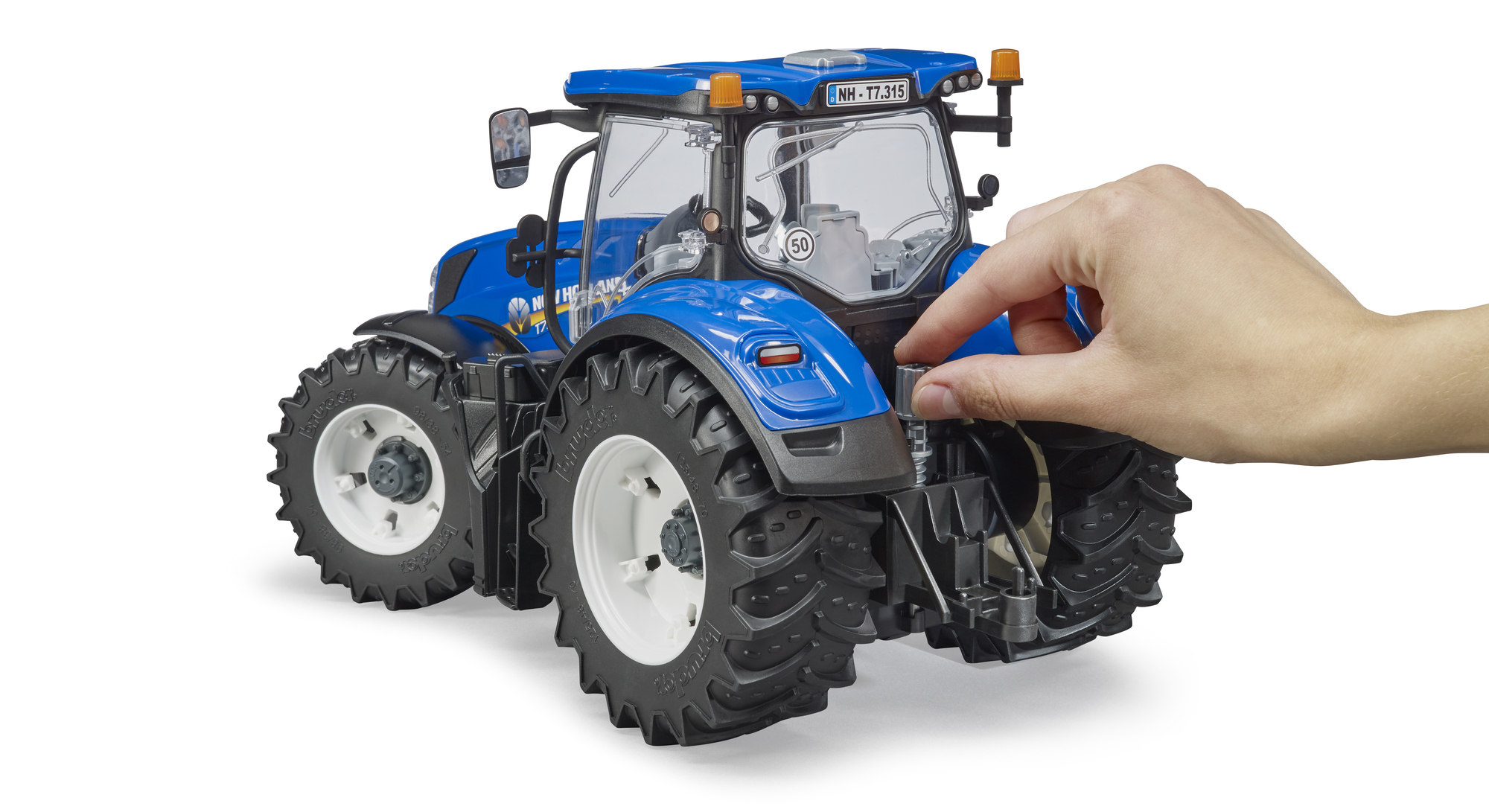 Niebieski traktor zabawka, ręka wchodzi w interakcję z tyłem traktora.