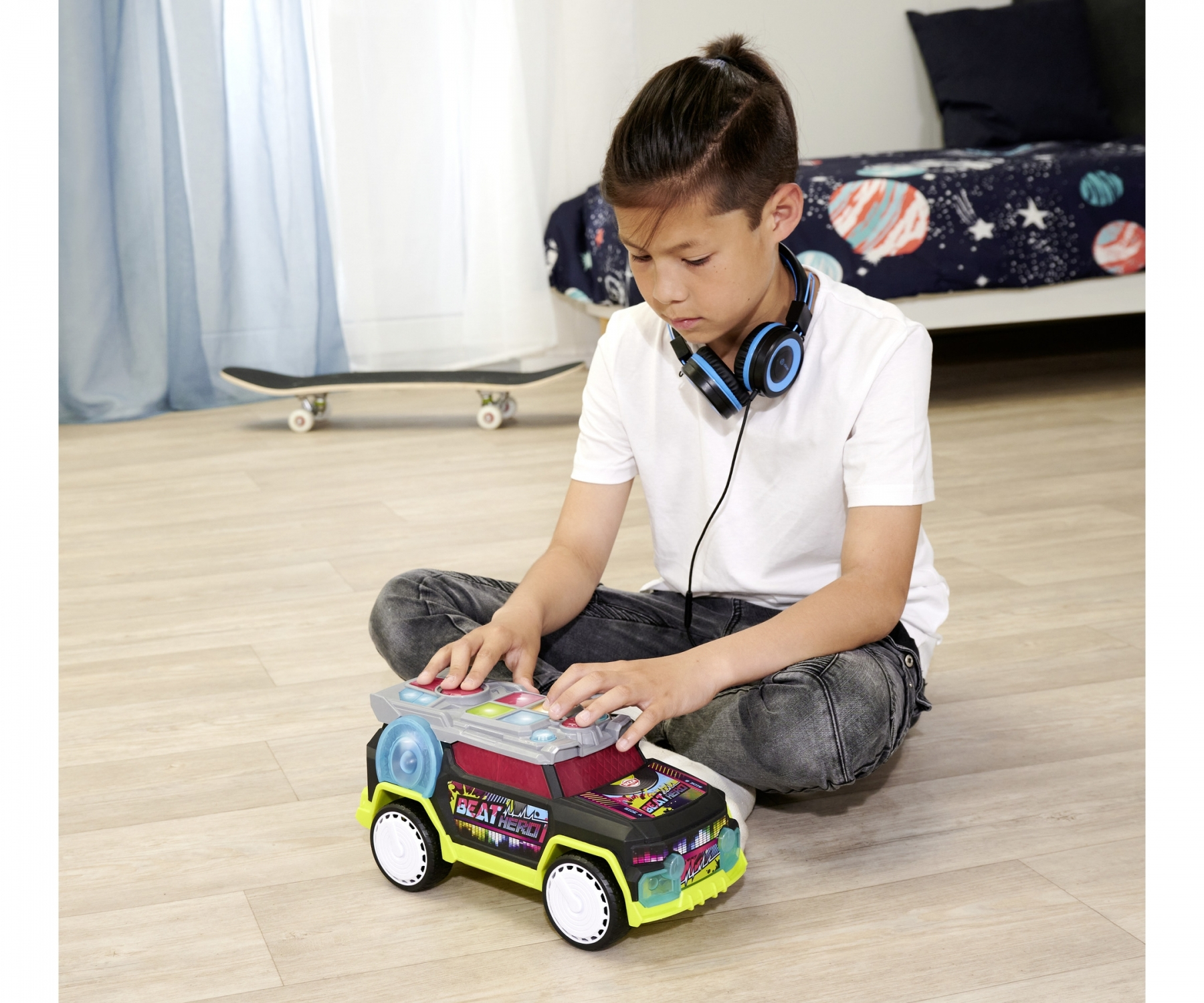 Chłopiec bawi się zabawką-samochodem. Samochód ma design stołu DJ-skiego i jest czarny, żółty i czerwony.