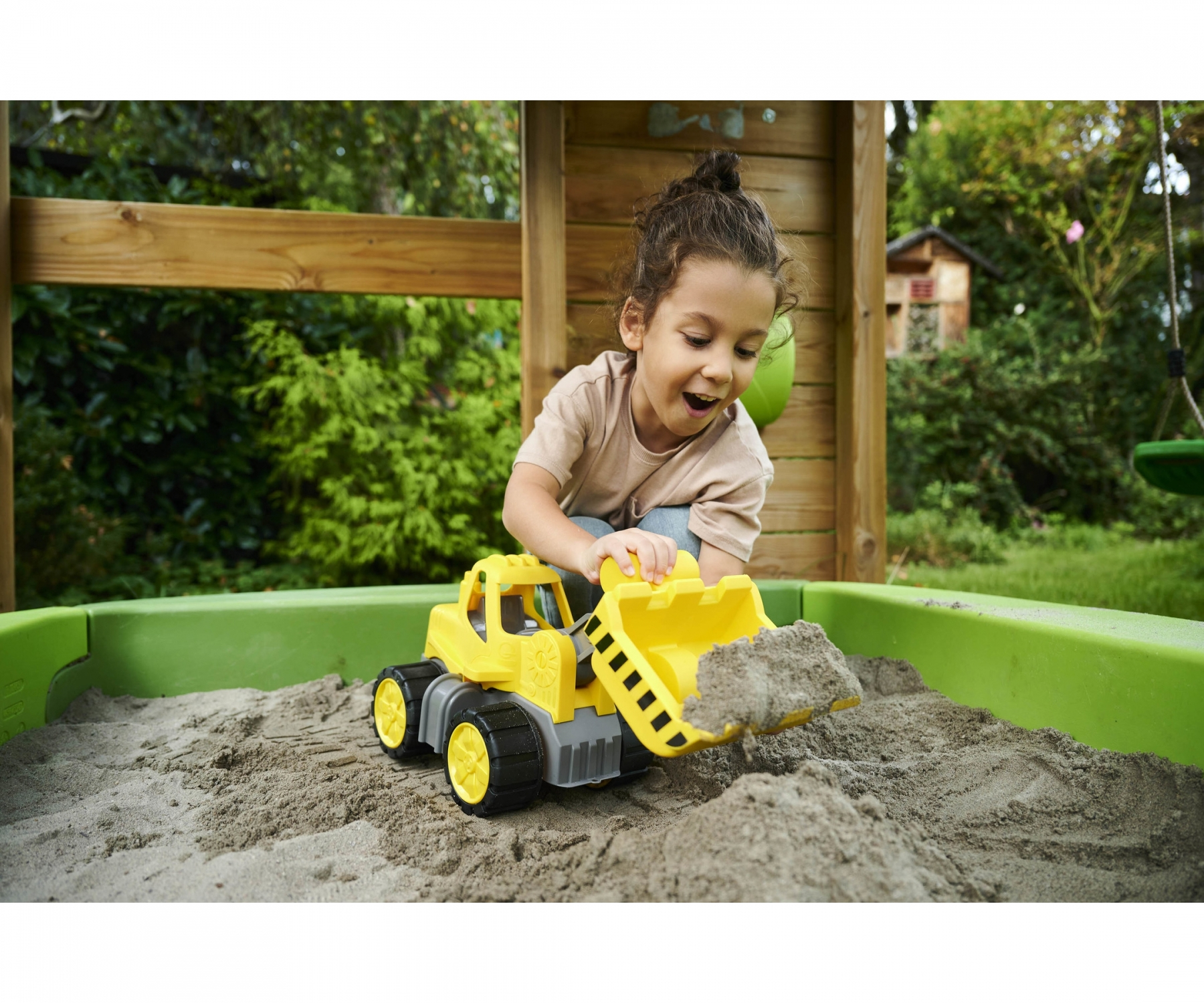 Dziecko bawiące się w piaskownicy z żółto-czarną zabawką - koparką.