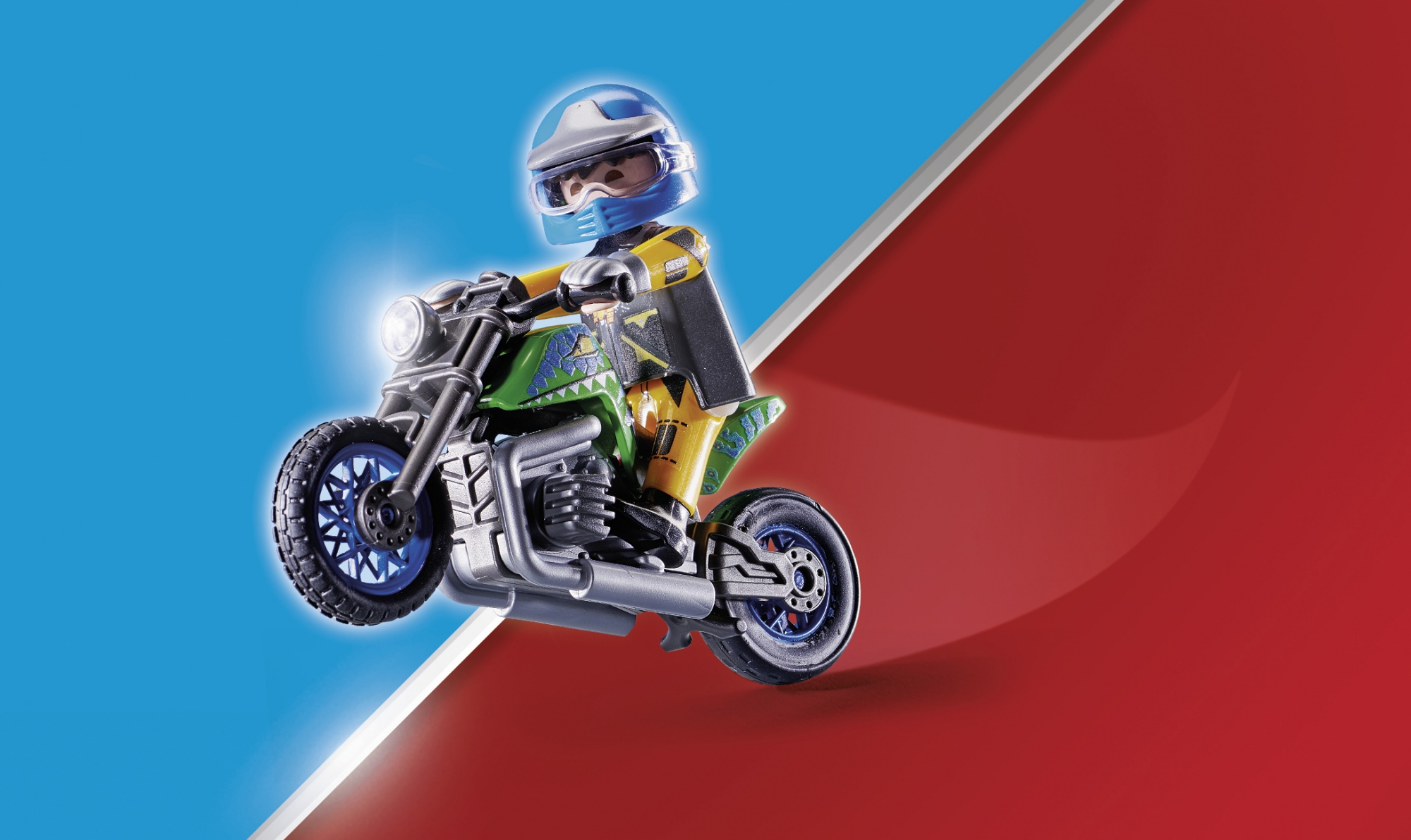 Figurka Playmobil na motocyklu, w dynamicznej pozie na czerwono-niebieskim tle.