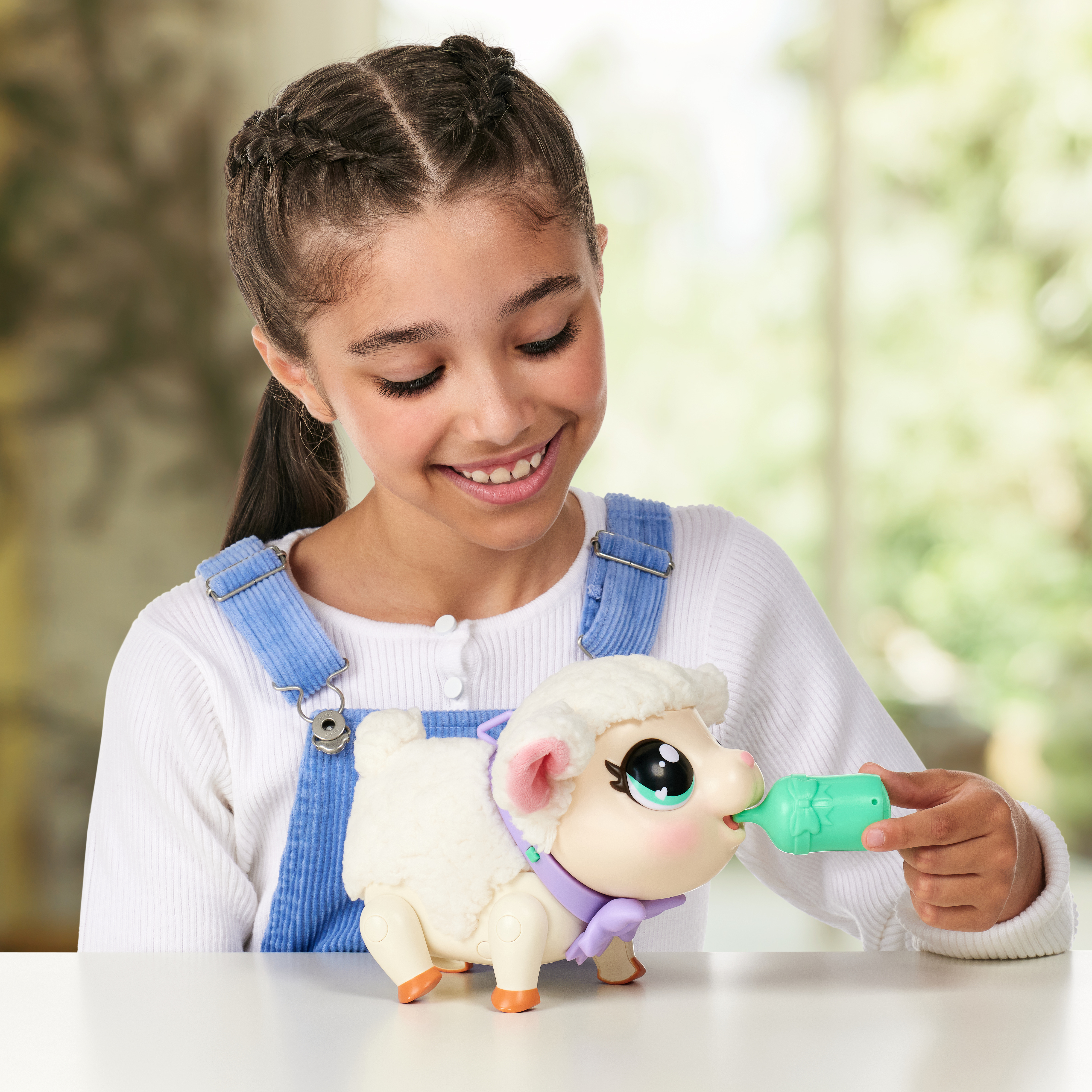 Dziewczyna karmi zabawkę owcę butelką. Owca jest biała z różowymi akcentami. Scena w pomieszczeniu.